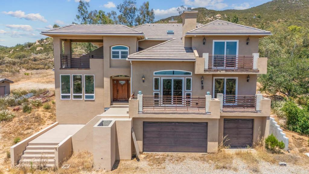 Welcome to this beautifully crafted 4 bed, 4 bath Craftsman-style estate nestled on over 5 acres of usable land in the serene hills of Jamul. Designed with versatility and space in mind, this home features a main-level bedroom with a full bath and private balcony, ideal for multi-generational living or guests. Inside, enjoy two spacious living rooms, a formal dining area, and a massive gourmet kitchen outfitted with an induction cooktop, built-in refrigerator, wine fridge, and ample cabinetry—perfect for hosting and everyday comfort. Dual AC units keep the home cool year-round, while the three-car garage includes an extra space ready for conversion into an ADU, studio, or workshop. APPROVED PERMITS/PLANS TO BUILD ADU AND SOLAR FOR OFF GRID LIVING. With endless possibilities, the expansive lot offers room to build an additional home, guest house, or even divide the parcels for future development. Whether you're dreaming of a private retreat, multi-family living, or a long-term investment, this property has the potential to do it all. Experience privacy, space, and opportunity—all just 30 minutes from downtown San Diego.
