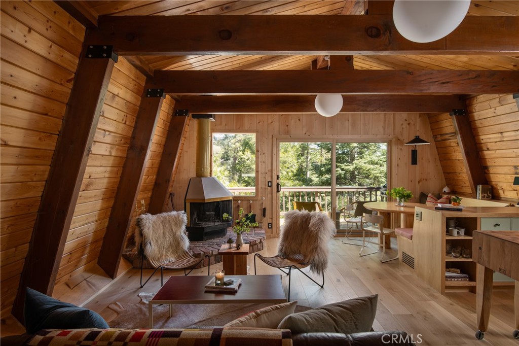 A uniquely custom cabin that pairs a quiet architectural presence with a rich interior palette and is enveloped by a lush environment, defined by craftsmanship and intention. Set beneath a distinctive gambrel roof, the residence offers a welcoming blend of warmth, texture, and high-end detailing throughout. Exposed wood beamed ceilings bring a sense of grounded elegance to the living room, where the original corner fireplace creates intimacy among the the flow of the space. Anderson wood-clad windows allow natural light to pour in, illuminating the home's curated finishes. The kitchen is a standout—anchored by honed Basaltina countertops and accented white oak cabinetry, with a Thor range and Retro Mod refrigerator offering a mix of modern performance and vintage styling. Fixtures include Brizo’s Odin faucets chosen for their sculptural minimalism. Zia tile backsplash adds a refined layer of texture and tone. A multi-functional banquette with white oak bench seating and custom cushions—upholstered in Perennials’ Raffia fabric by Legacy Custom Upholstery—adds thoughtful utility and charm. The main level features a Clé cement tile powder room adding artisanal character. Downstairs, the primary suite sits within the mature foliage, featuring a large picture window that frames the verdent exterior, creating a peaceful, light-filled retreat. A jewel box style bathroom is wrapped in mint penny tile, with a custom terracotta vanity. An additional cozy wood clad guest room is tucked in adjacently. Throughout the home, walls and closet doors are wrapped in flat-planked pine, echoing the warmth and texture of the exposed ceilings. The floors are finished in Vandyck wood, grounding the entire home in a natural, cohesive palette. A lower level expansive deck acts a second living space, and is shaded within the surrounding Dogwood, Cedar and Pine trees while an upper level balcony allows for an airy tree top experience with horizon views. Every element has been considered—from materials and hardware to color and form—to create a space that feels both elevated and deeply livable.