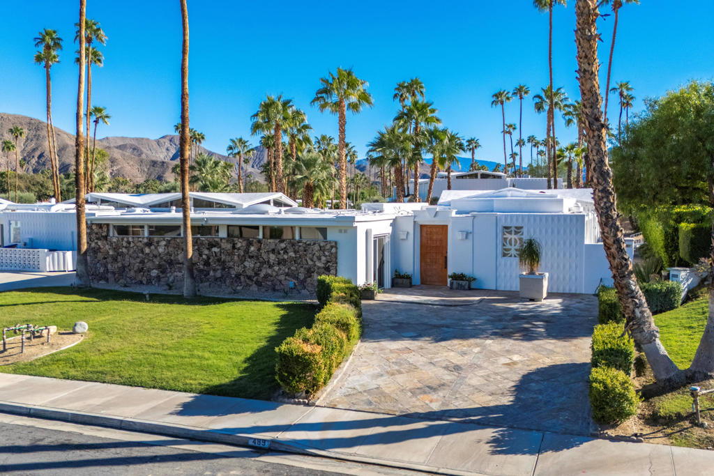 Where Mid-Century Modern meets Neoclassical design. This remarkable residence, located in the sought-after Canyon View Estates of South Palm Springs, is truly one-of-a-kind. Originally designed by famed architect William Krisel, the home features his iconic pop-up umbrella rooflines and clerestory windows, both hallmarks of a visionary who helped shape the Palm Springs modernist movement.The interiors showcase a stunning expression of neoclassical elegance. Hand-cut French limestone floors, laid on the diagonal from front to back, anchor the living spaces. Dramatic Mahogany beamed ceilings finished with gold leaf. Custom millwork includes raised and recessed matching-grain mahogany paneling in the dining room and second bedroom/den, walnut paneling in the third bedroom, and boxed-hinged cabinetry in the kitchen. The primary bathroom is appointed with filled travertine tile with black onyx inserts, and granite counters. Hidden doors and moving bookshelves create secret passageways, blending architectural surprise with function. The second bedroom is used as a den with a Murphy bed. The house has a newer hot water heater (2023) and a recoated roof (2025).Designed for both style and comfort, the residence offers an easy flow between living, dining, and entertaining areas, enhanced by abundant natural light. Canyon View Estates provides a serene desert setting with mountain views, community pools, and the architectural pedigree that has made the neighborhood one of Palm Springs' most celebrated. The community was recently used as the location for the feature film Don't Worry Darling.