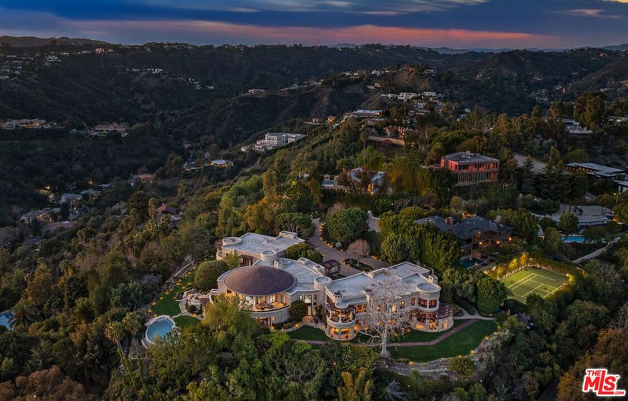 The Quincy Jones Estate - an extraordinary offering in prime lower Bel Air, sited on an approx. 2.3-acre promontory with sweeping 270-degree panoramic views. Custom built for one of the most iconic figures in music history, the estate is privately positioned behind gates at the end of a cul-de-sac, offering total seclusion with unobstructed vistas from the San Gabriel Mountains to the Pacific Ocean. A majority of the grounds are flat and usable, featuring a full-size lighted tennis court, circular motor court, rolling lawns, lush gardens, multiple verandas and patios, and an infinity-edge pool. Designed in collaboration with renowned architect Gerald "Jerry" Allison, FAIA celebrated for his global luxury hospitality work the residence was conceived as a personal retreat, merging resort-inspired design with bold scale and refined finishes. The circular central wing anchors the home, encompassing a grand living room with adjoining library, bar, and terrace. A sun-filled double-height atrium connects to a wine bar, tasting room, and cellar, flowing into an indoor garden. A game lounge and cabana open directly onto the pool terrace, completing the resort-style experience.The east wing houses the expansive primary suite - a private sanctuary with a luxe bedroom, spa-style bath, multiple walk-in closets, gym, den, and private balcony. This wing also includes a formal dining room, gourmet kitchen with butler's pantry, family room, and staff quarters. The west wing features three additional guest suites, including a junior primary with its own living room, dual bathrooms, walk-in closet, and terrace. Additional amenities include a state-of-the-art screening room, a professional office with reception area, a dedicated security office, and a gallery. The home is serviced by an elevator and multiple staircases, one in each wing. With a rich cultural legacy, this iconic estate has welcomed Hollywood royalty, global dignitaries, and legendary artists. Just minutes from Sunset Boulevard, it stands as one of the most exceptional view estates in all of Los Angeles offering rare privacy, pedigree, and scale.