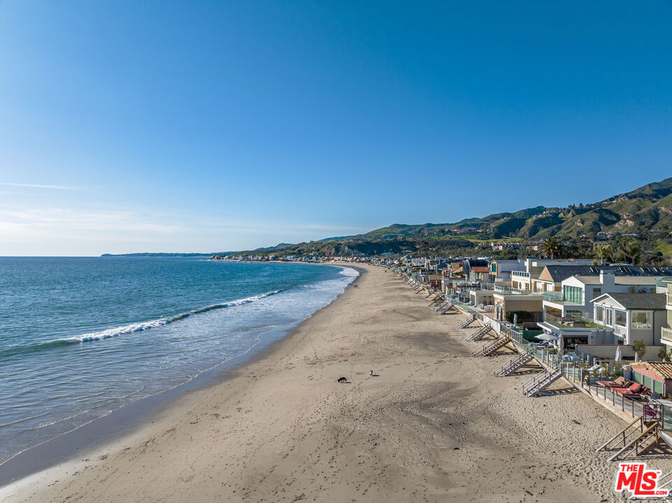 Exceptional opportunity on the sand inside the exclusive Malibu Colony guard gates. Grand scale throughout with beamed ceilings and lots of light. Beautifully appointed living room and family room both open up to the expansive outdoor entertaining space with a sunken jacuzzi tub just steps from the sand. The chef's kitchen boasts a large center island and a sunny breakfast area. Gracious primary suite with high ceilings, sitting area, and private oceanfront deck featuring beautiful ocean views up and down the coast. The primary bathroom includes dual vanity's with a massive rain shower and two additional bedroom suites on the second level. A rare grassy courtyard offers a pizza oven and BBQ for entertaining. Off the courtyard is a separate ocean view guest house with its own entrance, a living room, fireplace, one-bedroom suite, and lofted gym. Offering absolute privacy and security, this is the ultimate retreat moments from Malibu's renowned shopping and dining.