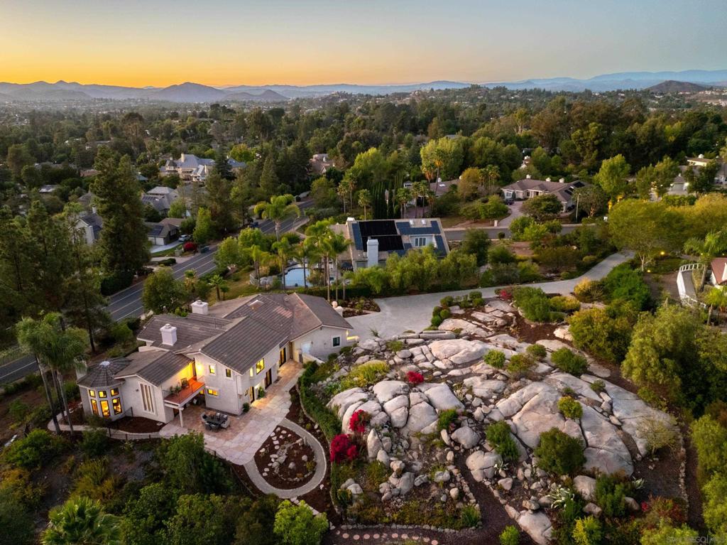 Tucked away in the exclusive enclave of Green Valley Knolls, this refined estate offers an elevated lifestyle where luxury meets nature on 1.17 serene acres. Spanning 3,699 sq ft, this custom built home is a private sanctuary with expansive mountain and hillside views that unfold with every sunset. A sweeping stone patio, energy-efficient new doors and windows throughout the home, and a completed property pro landscape design invite peaceful evenings under glowing skies. Step inside to discover airy, sunlit spaces with rich hardwood and tile floors, high ceilings, and a seamless indoor outdoor flow. French doors and new windows frame tranquil vistas, while the sophisticated, reimagined kitchen (featuring a high end oversized quartz island, new induction stove top, and custom details) anchors the heart of the home. The primary suite offers a retreat of its own, complete with a fireplace, dual walk-in closets, custom built-ins, and a private deck, ideal for morning coffee or evening stargazing. Four complete bathroom remodels showcase quartz counters, new vanities, upgraded lighting, and beautifully tiled showers, blending luxury with timeless design. Throughout the home, modern enhancements such as a whole house plumbing system with water safety controls, solar shades, and an upgraded irrigation system provide peace of mind and everyday ease. With no HOA, no Mello-Roos, and located within the top tier Poway Unified School District, this estate delivers an uncompromised blend of privacy, luxury, and convenience in one of Poway’s most sought-after neighborhoods.