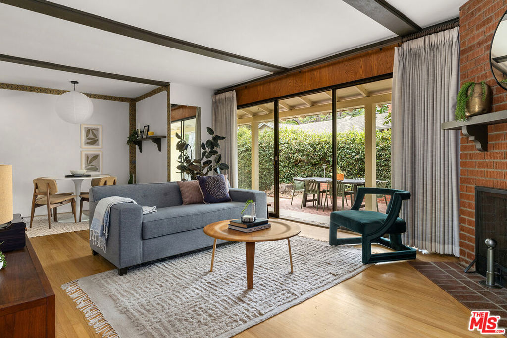 Tucked away in a delightful pocket of Studio City, this Mid-Century gem blends country charm with timeless character. Lovingly cared for by the same family since 1970, the home retains many original details, offering a warm and nostalgic feel throughout. A wall of glass doors and windows frames views of a charming brick patio shaded by lush greenery, creating a seamless indoor/outdoor connection. The living room's untouched brick fireplace and classic wood-paneled wall add vintage appeal, while hardwood floors flow throughout the home. The original knotty pine kitchen features updated appliances and a cozy breakfast nook with a large picture window. North facing windows fill the home with fantastic light. The home offers 3 spacious bedrooms, a main bathroom with a separate bathtub and stall shower, and a half bathroom. Many modern updates have been completed, including recently upgraded plumbing and HVAC systems. Additional features of the home include a spacious 2-car garage with easy access to the house, ample storage, a separate laundry room, and multiple lovely outdoor spaces. Set amongst a tree-filled backdrop that includes stunning deodar cedars and mature avocado and persimmon trees, this is California living at its best. Just a short stroll to Studio City's beloved Beeman Park, Whole Foods, Studio City library, Hugo's Restaurant, and more, this property offers a rare opportunity to enjoy an unbeatable location at an exceptional value.