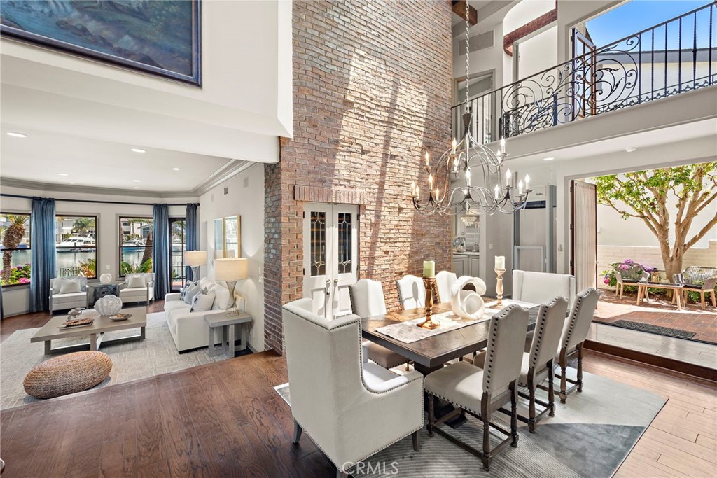 Welcome to 648 Harbor Island Drive, a waterfront sanctuary in the heart of Newport Beach’s exclusive Promontory Bay. This bespoke residence captures the romance of Old World European architecture with the ease of modern coastal living all set along 50 feet of shimmering bay frontage.
Gracefully constructed with slate roof, hand-finished brickwork, and leaded glass accents, the home offers approx. 3,898 square feet of richly detailed interiors across 4 bedrooms and 6 bathrooms. Timeless design elements include vaulted ceilings, hand-hewn wood beams, and artisan wrought ironwork creating a sense of warmth, sophistication, and craftsmanship rarely found today. At the heart of the home is The Pub, a signature entertaining space reminiscent of a traditional English club room complete with a custom wet bar, lounge seating, and French doors that open to a private patio. The formal dining room is a dramatic showpiece with cathedral ceilings and a brick accent wall stretching two stories high. The kitchen is as refined as it is functional, featuring Bosch and Viking stainless steel appliances, custom cabinetry, and generous prep space for culinary gatherings. Step outside to the expansive bayside terrace, a true extension of the home with multiple seating and dining areas designed to take full advantage of the tranquil water views. Your private dock accommodates two yachts up to approx. 55 feet, with additional space for a 3rd boat tender or Duffy making it effortless to launch into the harbor at a moment’s notice. Whether you’re entertaining by sunset, cruising the coastline, or simply relaxing in the ambiance of this timeless retreat, 648 Harbor Island Drive delivers the rare combination of European charm, waterfront presence, and Newport Beach prestige.