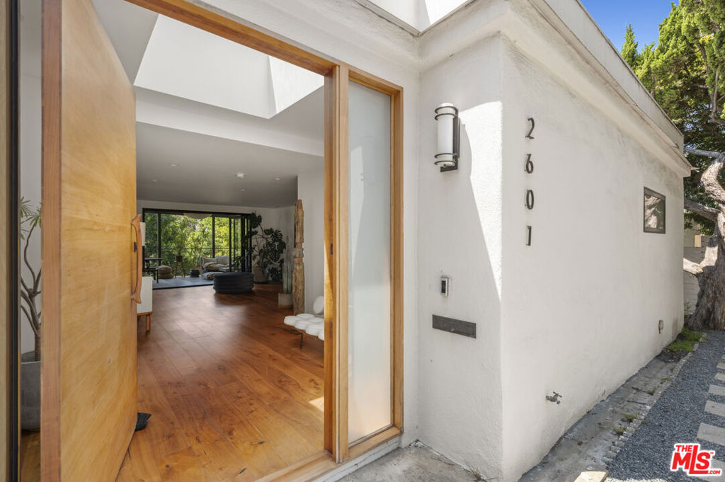 This recently remodeled designer California dream home is tucked away in one of Silver Lake's most sought-after pockets. Enter through a large walnut pivot door into rooms featuring walnut hardwood floors and exposed beam ceilings, with French doors in every room. Experience the tranquil oasis of your backyard, filled with lush eucalyptus trees, bamboo, and a drought tolerant podocarpus hedge that surrounds the home for complete privacy. Wake up to the sound of birds chirping and watch hummingbirds drink from the honeysuckle all in your own backyard. The living and dining area opens, via a bi-fold sliding door, onto a 338sq ft covered balcony, perfectly staged for enjoying California's year-round outdoor dining. The en-suite primary bath features a large standalone soaking tub, a high-end contemporary bidet, a dual vanity sink, and a spacious walk-in closet with custom ash wood built-ins and handpicked imported hardware. Spanish tiles ripple along the walls like sand, evoking the feel of the sea. You can also enjoy an outdoor shower or soak in your SoftTub spa surrounded by bamboo after relaxing in your designer infrared sauna. The open kitchen layout, centered around a massive one-piece Carrara marble island, faces a classic limestone working fireplace in the den designed to make the kitchen the heart of the home for entertaining guests. While the home includes central air and heat, it is so well insulated that it often feels like an adobe, naturally cooled by the Pacific Ocean breeze. This retreat-style home has the charm of Laurel Canyon, yet it is set close in proximity to some of the city's most coveted destinations: the Silver Lake Reservoir & dog park, LA River bike trail, and some of the finest shops, restaurants, cafes, and music venues that bring New York vibes to Los Angeles. Blueprints for all recent remodels, along with plans and renderings for a downstairs addition with a pool, are available to interested buyers only.