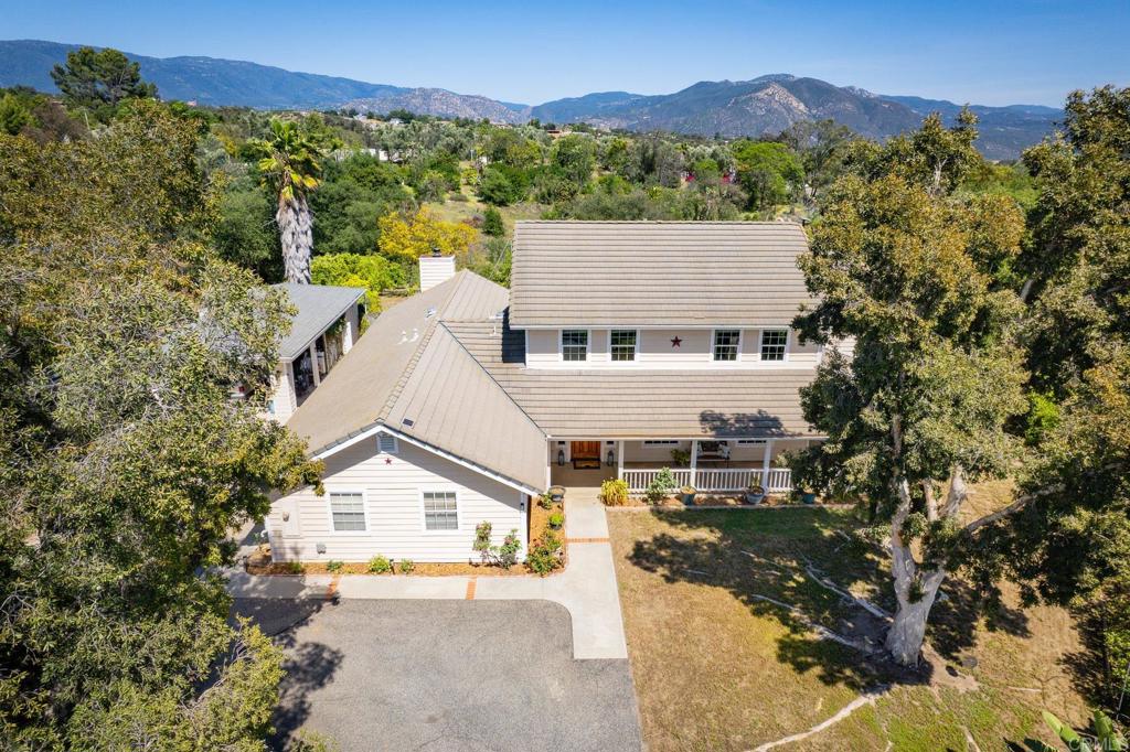 Discover the charm of cozy country by at 15519 Villa Sierra Road, nestled in a peaceful cul-de-sac in Valley Center. This 4-bedroom, 3-bath home offers over 3,000 sq ft of warm, inviting living space on 2 fully usable acres. From the moment you enter the gated drive, you’ll feel welcomed by the wraparound porch, mature landscaping, and serene setting. Inside, you’ll find a spacious layout with a formal living and dining room, a large family room with vaulted ceilings and a high efficiency wood-burning fireplace insert, an updated kitchen with a large walk-in pantry—perfect for storing your favorite recipes and homegrown goods. Downstairs features a full bedroom and bath, while upstairs includes a generous primary suite (14' x 18') with soaking tub, walk-in shower, and dual sinks, plus two additional bedrooms (12'x 14') with a shared oversized bath (10' x 15') also with dual sinks. Enjoy reliable AT&T Fiber high-speed internet, a central laundry room with laundry chute from upstairs, and bonus storage throughout. Step outside to your very own Secret Garden with seasonal flowers, shaded seating, and over 80 fruit, nut, and berry trees. The property is fully fenced and cross-fenced—ideal for animals or future additions like a barn, workshop, ADU, or horse setup. There’s even a ready-to-use chicken coop! A true retreat for those seeking space, nature, and simple country comfort.