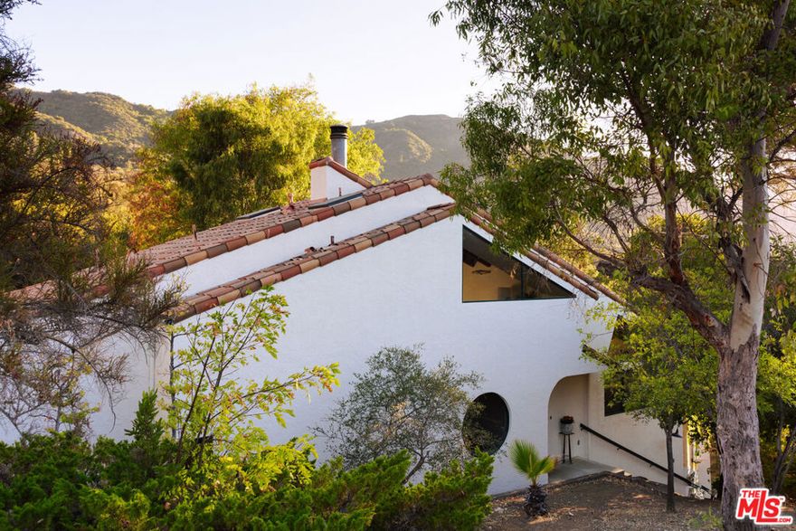Welcome to 25620 Nebo Drive. Tucked away in the peaceful, coveted community of beautiful Monte Nido, this 3-bedroom, 3-bathroom Architectural Spanish home is filled with extraordinary natural light. Every window frames a viewoffering unmatched privacy and breathtaking mountain vistas. Backing up to untouched open space on a half acre, it feels like your own secluded retreat, yet it's just minutes from Malibu's beaches, Calabasas' shops and dining, and Las Virgenes award-winning schools. Inside this special home, you'll be awed by the seamless flow of space designed for everyday living and entertaining. Freshly painted inside and out, with beautiful wood flooring, and countless delightful details that make this home truly special. The spacious living room showcases soaring cathedral wood ceilings, dramatic architectural windows where light dances across the walls, and a cozy fireplace for winter nights. The open kitchen, with freshly painted cabinets, features elegant countertops and tile backsplash, along with abundant storage and counter space. It opens to a warm family room with French doors leading to the large backyard and sparkling pool. The formal dining room boasts a statement round window that perfectly brings the outdoors in. Also downstairs are two well-sized guest bedrooms with skylights, a stylish powder room, and a large guest bath with double stainless steel sinks and Carrera marble countertops. Upstairs, the private primary suite impresses with wood cathedral ceilings, expansive architectural windows, and its own fireplace. The ensuite bathroom includes his-and-her spaces and leads to "the closet of your dreams" a massive walk-in closet (not included in the square footage). Outdoors, you'll find inviting spaces for entertaining, play, and relaxation. Surrounded by the magic of the Santa Monica Mountains, with a trailhead just steps from your front door, this property is truly a gateway to nature. Whether gathering with family or simply soaking in the serenity, this home captures the very essence of Monte Nido living.