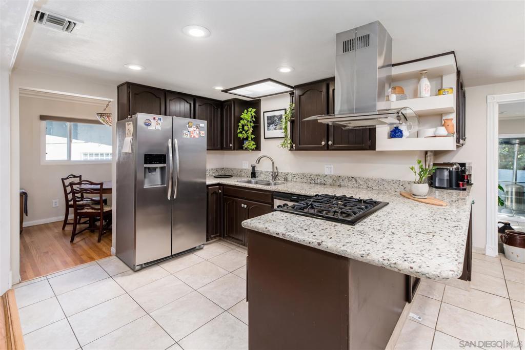 Get ready to fall in love with this spacious College Area family home featuring dual master suites, hardwood floors, carpeted family room with fire place and a stunning kitchen with rich dark-stained cabinetry. The deep tones contrast beautifully with lighter finishes, creating warmth, elegance, and timeless style. Skylights for natural light, granite counters, stainless steel appliances. Light-filled living areas flow seamlessly to a private backyard oasis with mature lush landscaping—perfect for entertaining or relaxing. Ideally located just minutes from SDSU, dining, shopping, and more. See supplemental for further details. This spacious turnkey 4-bedroom, 3-bath family home has been thoughtfully updated and meticulously maintained. Dual master suites make it ideal for multi-generational living, hosting guests, or creating a private retreat. The open layout features hardwood floors and tile, abundant natural light, and a renovated kitchen with granite countertops and stainless steel appliances. Comfort and efficiency come with dual-pane windows, a Nest thermostat, skylights, a solar tube, and fully owned solar panels. Major updates add peace of mind, including HVAC replacement (2016), roof (2017), new water heater (May 2025), updated wastewater lines, and Rhino Shield exterior paint with transferable warranty. The laundry area has been conveniently relocated to the main level under a covered space, and the 2-car garage offers ample added storage. Outdoors, enjoy a private backyard oasis with mature landscaping, perfect for relaxing or entertaining. Ideally located minutes from SDSU, dining, shopping, and major freeways, this home combines modern comfort with lasting value.