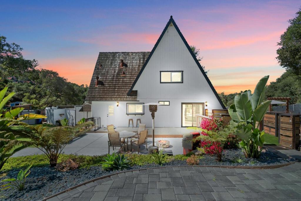 This inviting chalet-style home blends rustic charm with modern comforts. Inside, soaring high open-beam ceilings and warm laminate floors create an airy, welcoming atmosphere. The kitchen features granite countertops, stainless steel appliances, and a cozy eating nook, perfect for casual meals. A comfortable living room centers around a fireplace insert, while a wrought-iron spiral staircase adds a distinctive architectural touch. Updated bathrooms provide a fresh, contemporary feel. Set on a usable 30,492 SF lot, the lush backyard is an entertainers dream offering multiple patios, room for a playset, putting green, and a variety of fruit trees, including lemon, orange, and nectarine. A dedicated dog run keeps furry friends happy; RV parking and a detached 2-car garage provides ample parking and storage. This home is ideal for those seeking both style and space in a picturesque setting with easy commute access to Morgan Hill, San Jose, Monterey, or Santa Cruz.