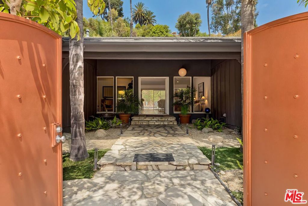 Located in the highly desirable Lake Hollywood Estates, this celebrity-owned retreat offers complete privacy. Thoughtfully designed with high walls that encompass the property, beautiful landscaping, and multiple walls of glass, ensuring that you will experience a sense of serenity the moment you enter through the gates and arrive at the secluded front courtyard door, surrounded by lush greenery. The living room and dining room enjoy high vaulted ceilings, recessed lighting, a fireplace, and an expansive view of the backyard through double sets of glass doors. The connecting kitchen has gorgeous quartz counters with a center island, beautiful, warm-toned wood cabinetry, stainless steel appliances, and flows into the large family room. Three guest bedrooms that all offer plenty of soft natural light, with two of the bedrooms having been converted into one large bedroom and office combination and that can easily be converted back to two separate bedrooms. The sumptuous master suite is enormous, featuring high ceilings and spacious closets with storage space. It also features double sets of glass doors for abundant natural light and stunning views of the pool and backyard. The master bath is luxurious, featuring a double shower, separate spa tub, double vanity, and a wall-sized window that offers a fabulous view of the backyard. The oversized backyard is where the magic happens! This expansive environment is perfectly designed for relaxing or hosting large gatherings. A spacious pool is the centerpiece of the backyard and features a dual waterfall that produces a calming sound throughout the yard and home. An additional gated side yard is also a perfect play area for kids or your favorite pets. It's an ideal location, with hiking trails, the lake, the park, and the Hollywood Sign. Shown by appointment only. There will be no public open house. Hurry, a rare opportunity to own a bit of Hollywood history.