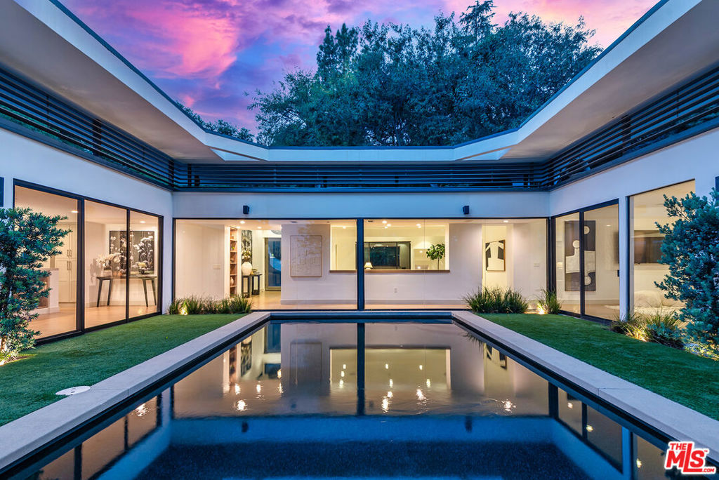 Nestled in the prestigious Royal Oaks neighborhood of Encino, this fabulous single-story meticulously renovated Mid-Century retreat offers the perfect blend of privacy, luxury, and timeless design. Accessed via a gated, long private driveway lined with trees, this stunning home boasts sweeping views of lush treetops and the valley beyond. With nearly 4,700 square feet of living space, the open floor plan seamlessly flows around a sparkling pool, creating an entertainer's dream. The home features 4 en-suite bedrooms, each with its own bath, including a grand primary suite with an attached office/gym, an expansive closet, and a spa-like bath. A romantic fireplace adds to the serene ambiance of the primary suite. The beautifully appointed kitchen, with stainless steel appliances, flows into the family room, and opens to multiple outdoor living areas, including a built-in BBQ and a cozy fire pit with custom seating. Skylights and large windows flood the space with natural light, creating an airy and inviting atmosphere. A wonderful den or sitting area unites the bedrooms, offering a perfect space to unwind. Set on over an acre of park-like grounds, this architectural gem offers unparalleled privacy, with water features, a waterfall, and a whole-home water filtration system. With its perfect flow for entertaining and tranquil oasis setting, this home is truly a must-see.
