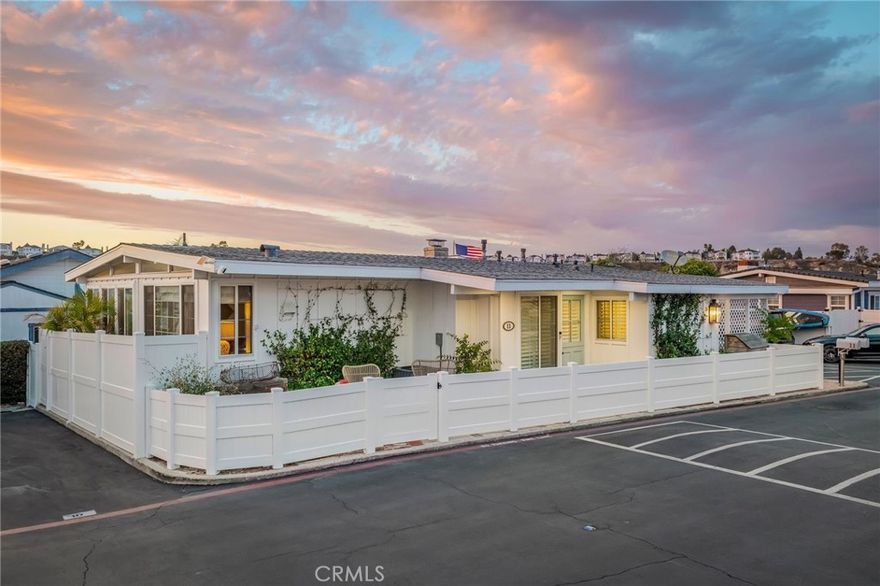 Experience the ultimate Newport Beach lifestyle in this serene, sun-drenched waterfront bungalow overlooking the Back Bay. Every moment here feels like a coastal daydream — from coffee at sunrise on your wraparound porch to golden-hour dinners al fresco, as the sun melts into the water. This renovated 2-bed, 2.5-bath retreat blends modern design with timeless coastal charm. Step inside to an open-concept living area with beamed ceilings, antique Spanish tile floors, and a cozy gas-burning fireplace. Large picture windows invite endless bay views and bathe the space in natural light. The chef’s kitchen is a showpiece of craftsmanship — featuring a full Bertazzoni Italian appliance suite, custom cabinetry, and designer finishes. Every inch of this home was reimagined with intention: solid wood doors, Thomas O’Brien lighting, bronze hardware by Ashley Norton, and curated textiles by Kelly Wearstler. All bathrooms were recently redesigned with hand-crafted tilework, luxe fixtures, and ample storage. A dedicated office nook overlooks the bay — perfect for those who work (or daydream) with a view. Step outside to a wraparound waterfront deck designed for effortless entertaining — from evening wine by the firepit to brunches overlooking the private dock. The home is fully enclosed with new vinyl fencing and includes a covered parking space, Sonos sound system with in-wall speakers, a security system, and even a private dog run. Located on prime second-row waterfront, you’ll enjoy views with below-market space rent — and best of all, no property taxes! As part of Bayside Village, residents enjoy resort-style amenities: two sparkling pools, two spas, gym, firepits, BBQ areas, a fenced dog park, and a clubhouse. You’re just minutes from Balboa Island, Fashion Island, and Newport’s best beaches and dockside dining. This isn’t just a home — it’s a lifestyle of waterfront luxury, effortless entertaining, and sunset serenity in the heart of Newport Beach.