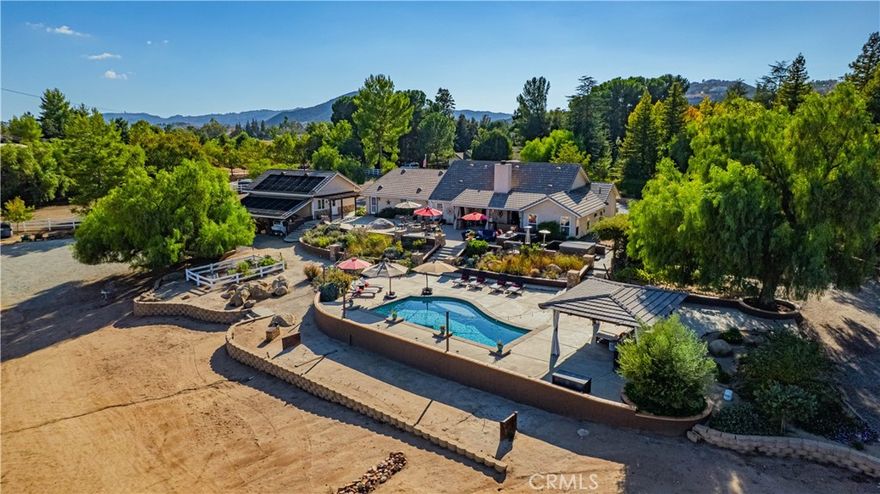 Land, Luxury & Legacy in La Cresta —  | Experience the ultimate in Murrieta luxury living at this exceptional La Cresta estate, designed for those seeking space, privacy, and multi-generational flexibility.  This property must be experienced to be appreciated; the photos simply can’t convey its stunning setting, craftsmanship, amenities and lifestyle potential. *Watch the virtual tour for a taste of that experience*  Situated on 5.14 fully usable & fenced acres at the end of a quiet cul-de-sac, this rare property offers DIRECT access to trails and showcases the perfect balance of country charm and resort-style amenities. Power supported by a 62-panel fully owned solar system, the estate features two single-story residences, entertainer's pool oasis, a custom barn, and a 3,498 sq ft workshop/ large vehicle garage with an MX-10 ACX auto lift and dual roll-up RV doors primed for conversion into a large equestrian barn (see supplement for inspiration). The main residence is expansive offering three bedrooms, with two bonus spaces: a separate office with built-in cabinetry, plus a gym/game room. Floor plan includes an open-concept family room and kitchen with elevated ceilings and designer fixtures. It also includes an oversized two-car garage plus an additional detached 2.5-car garage. The second home offers three bedrooms, two baths, plus an office with built-in cabinetry, and an attached two-car garage. The second home is ideal for multi-gen living, guests, or rental income. Equestrian facilities include a custom two-stall shedrow barn with tack and feed rooms, automatic waterers and turnout stalls. The property is perfect for the equestrian enthusiast with 3 fully fenced pastures, a round pen & DIRECT access to riding trails - with room to expand and add more pastures, arena, or whatever you envision. Outdoor amenities elevate the lifestyle: a solar-heated pool with waterfalls, above-ground six-person spa, outdoor barbecue kitchen, poolside cabana, two fire pits, chicken coops, raised garden beds & dual 5,000-gallon water storage tanks. This picturesque property is all framed by panoramic hill and mountain views. This La Cresta estate offers unmatched peace, privacy and functionality, located just minutes from award-winning schools, shopping, and freeway access. Discover why La Cresta remains one of So Cal’s most desirable equestrian communities. It is a place where land, lifestyle, and luxury truly come together. Square footage not taped, buyer to verify.