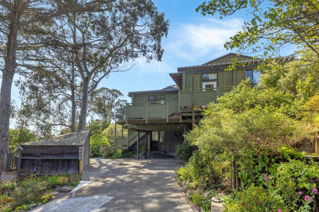 A hidden gem in Carmel, this redwood home was thoughtfully designed in the mid-1960s by George Beck, a local builder and artist inspired by Frank Lloyd Wrights organic and mid-century modern architecture. Crafted for his own family, the home reflects Usonian ideals with redwood-framed glass doors, a flowing indoor-outdoor layout, and a rare connection to the land. The upper level of about 1,540 sq ft offers two bedrooms, 1.5 baths, a modern kitchen, and a dining room with garden views. Expansive windows artistically frame views of hills and beautiful trees, flooding the home with natural light. Below, a separate entrance leads to a flexible 510 sq ft two-room suite with a full bath, ideal for a home office or guest retreat. Three decks provide space for outdoor living and reflection, with views across the rolling hills of Fish Ranch. Garden paths wind through a tapestry of succulents and seasonal blooms, planted and lovingly tended by the original family. Just minutes from Carmel Beach and the charming boutiques of Carmel-by-the-Sea, this home offers a Big Sur-like sense of escape with the convenience of Carmel living.