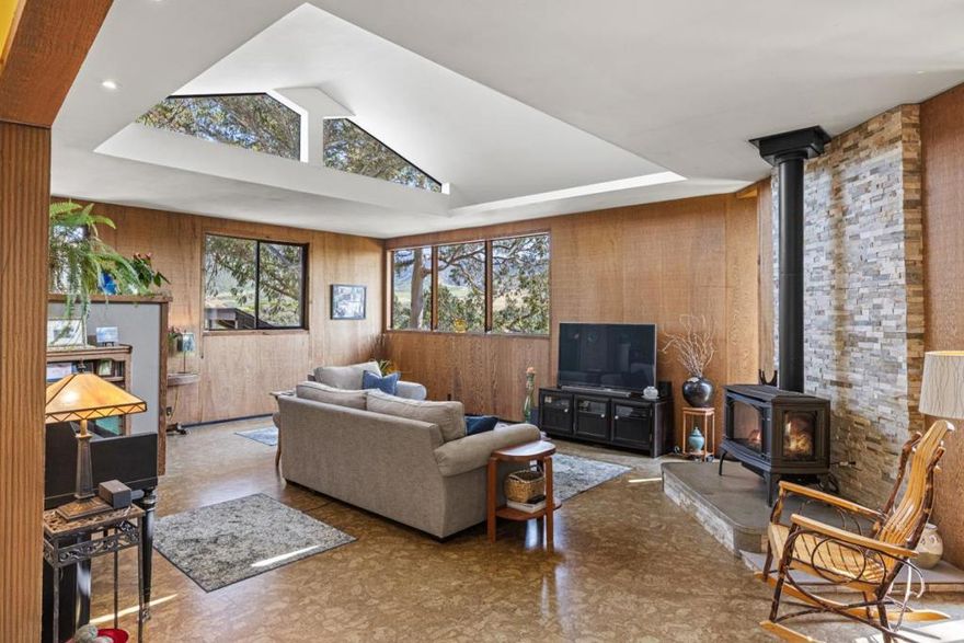 Mid-century redwood home on a Carmel hillside with views, sunlit interiors, and terraced gardens. Main level offers 2 bedrooms and 1.5 baths; below, a separate permitted studio with 1 bath and private entrance, minutes from Carmel-by-the-Sea beaches, dining, and trails. Set among terraced gardens and soft coastal light, this distinctive mid-century home captures the essence of Carmels creative landscape. Built in the mid 1960s from locally sourced redwood, its design was inspired by Frank Lloyd Wright's Usonian principles. Clerestory and intentionally symmetrical windows plus tall glass doors frame the surrounding landscape as living art.  The main level offers about 1,528 sq ft of airy living space with decks overlooking colorful, seasonally blooming gardens. Below, the permitted studio's flexible 510 sq ft layout with full bathroom makes an ideal guest suite, office, or artistic retreat. Lovingly cared for by one family since new, the property blends architecture, nature, and creative spirit in an exceptional location near white sand beaches.