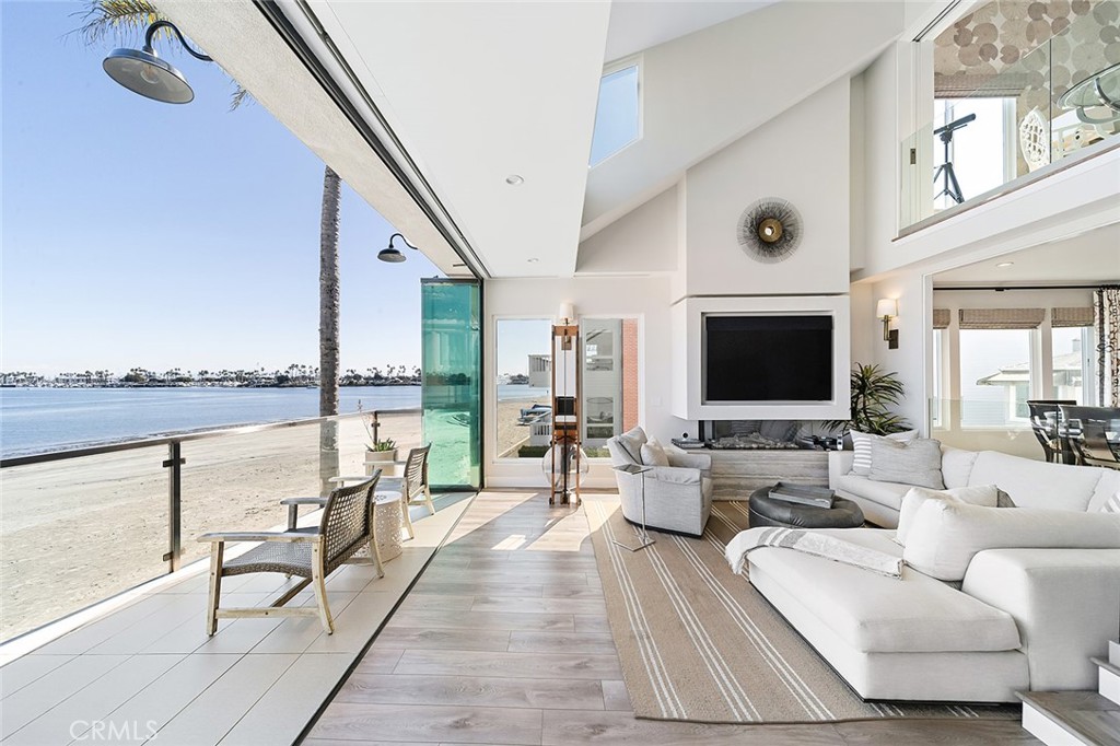 This home redefines extraordinary! Situated at the widest part of Alamitos Bay, it offers breathtaking views that stretch from snow-capped mountains in the winter to sailboats and paddleboarders gliding across the water year-round. A complete remodel elevates this residence beyond compare. The second floor sunroom seamlessly opens to the front balcony through an 18-foot glass panel door, inviting in the stunning scenery. Whether relaxing by the fireplace beneath vaulted ceilings with surround sound, or enjoying a drink at the adjacent wet bar, you’ll always have a front row seat to the beauty outside. Beyond the sunroom, the formal dining room flows effortlessly into a chef’s dream kitchen, featuring top-of-the-line appliances, custom cabinetry, and sleek Neolith countertops. For a more intimate retreat, the den offers a state-of-the-art entertainment experience with a 75” TV, custom soundbar, subwoofer, and Dolby 5.1 surround sound, part of the whole-home audio system. The den shares a wall with a second bedroom and a full bath is just down the hall. Take the elevator to the top-floor primary suite, a private sanctuary with bay views, a six foot gas fireplace with ambient lighting, a spacious walk-in closet, and a convenient stackable laundry. The spa-like primary bath is a masterpiece, complete with a soaking tub, steam shower, separate rain shower, private water closet with an electric Toto toilet, and a striking corner window framing the view. The ground floor expands the home’s versatility, offering a second living room, a third bedroom, a kitchenette, a full bath, and direct access to the two-car garage and double driveway. Every inch of this home has been designed to maximize comfort, luxury, and the incredible waterfront setting.