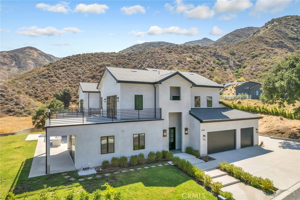 Perched on a private 3.87-acre lot, this newly constructed luxury estate blends sophisticated design with the natural beauty of its hillside surroundings. Offering 5 bedrooms, 5 bathrooms, and 5,446 square feet of meticulously crafted living space, this two-story residence delivers comfort, elegance, and functionality at every turn.
Step inside and be greeted by soaring ceilings, wide-plank oak wood flooring, and a light-filled open layout. The formal dining area leads effortlessly into a grand living room centered around a sleek electric fireplace with both heating and cooling functions—perfect for year-round comfort. Oversized sliding doors invite indoor-outdoor flow, revealing a covered patio ideal for entertaining.
The heart of the home is the chef’s kitchen, featuring a stunning quartzite waterfall island, custom oak cabinetry, and abundant storage. Just off the kitchen, a spacious three-car garage with epoxy flooring adds everyday convenience.
The main level also includes a well-appointed guest suite with ensuite bath, perfect for visitors or extended family.
Upstairs, the expansive primary suite is a true retreat with its private balcony showcasing sweeping hillside views, an oversized walk-in closet, and a spa-inspired bathroom complete with a soaking tub, glass-enclosed shower, and dual vanities. Three additional bedrooms, 2 of which has walk-in closets, are thoughtfully positioned for privacy, along with a full laundry room and utility sink.
Outdoors, the grounds have been thoughtfully prepared for both leisure and future expansion. A graded backyard pad offers potential for a pool, guesthouse, or ADU, while a built-in BBQ and custom hardscaping make entertaining effortless.
With space, style, and serenity, 26474 Ranch Creek Rd is a rare offering—perfect for those seeking upscale living in a private, expansive setting just minutes from city conveniences.