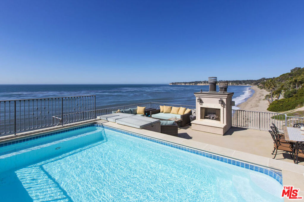 Crafted with exceptional attention to detail, this coastal residence is a masterclass in quality construction and timeless design. Expansive living spaces exude warmth and elegance, featuring custom finishes such as antique French stone floors reminiscent of sun-washed shores, soaring ceilings, and walls of glass that invite in natural light and ocean breezes. The gourmet kitchen is outfitted with top-of-the-line appliances and seamlessly connects to an oceanfront dining area and generous living room an idyllic setting for effortless beachside entertaining. The primary suite offers a serene private retreat with rich hardwood flooring, dual walls of disappearing glass doors that open to a private balcony, and a luxurious bath with hand-laid mosaic tile, a large shower, separate soaking tub, and an expansive walk-in closet.Four additional bedrooms provide ample accommodations, while a dedicated movie room and a library with built-in desk and reading nook offer versatile spaces for relaxation and creativity. A rooftop deck crowns the home, complete with a heated pool, spa, outdoor kitchen with built-in BBQ, and a fireplace perfect for enjoying the coastal lifestyle in style.