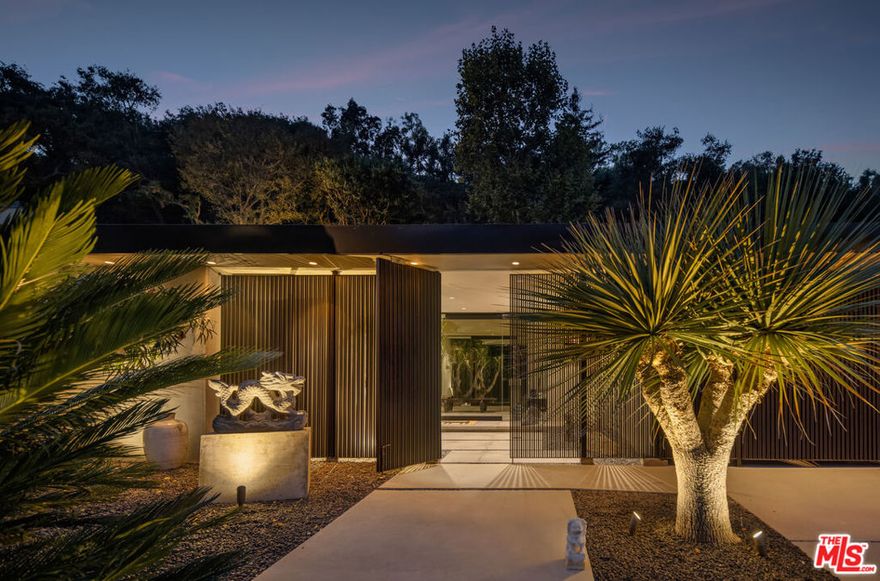 Recently rebuilt with intention and the highest level of craftsmanship, this reimagined mid-century retreat captures the rare balance between organic calm and architectural precision. The front grounds - composed by noted landscape architect Garett Carlson - frame the residence with lush, sculptural greenery and zen-inspired paths.Inside the secure gated entry, light moves fluidly across Venetian plaster walls, creating a tranquil rhythm throughout the residence. The formal living room serves as the centerpiece - anchored by a floor-to-ceiling bronze mirror fireplace and piano - where expansive glass panels open completely to the outdoors, merging home and landscape into one continuous environment. The kitchen is equal parts performance and display: new Miele appliances including built-in coffee, microwave, and concealed refrigerator/freezer, Wolf range and beautifully maintained stone counters. An adjacent glassware showcase and bar serve a second living area, also opening to the outside for seamless entertaining. The adjacent wine lounge adds a full modern bathroom and temperature-controlled refrigerator to the space, while a richly appointed powder room with a carved stone basin and dedicated laundry room complete the wing.Floor-to-ceiling sliders run the length of the main rooms, opening to an outdoor oasis designed for effortless gatherings: a large pool and spa set against lush California greenery, an alfresco kitchen and BBQ with generous dining deck, a separate seating area wrapped around a fire pit, and pockets of quiet landscape throughout. The primary suite extends directly to the hammock terrace and pool, and features a dramatic two-level, custom dressing room/closet, along with a spa-caliber bath appointed with rare Italian onyx dual vanities and a glass rainfall shower. A second bedroom enjoys its own bath with soaking tub and rainfall shower and opens to a private patio and fitness area. A third room - currently configured as the expansive primary closet  offers flexibility for a future guest suite if desired.Every system was carefully renewed between 2020 and 2023, including new roofing, solar energy, and a high-efficiency HVAC with linear diffusers. Additional amenities include a sculptural metal slatted two-car garage with ample storage, and total privacy achieved by the enveloping landscape and design. The result is a refined indoor-outdoor retreat where art, light, and craftsmanship are the constant.