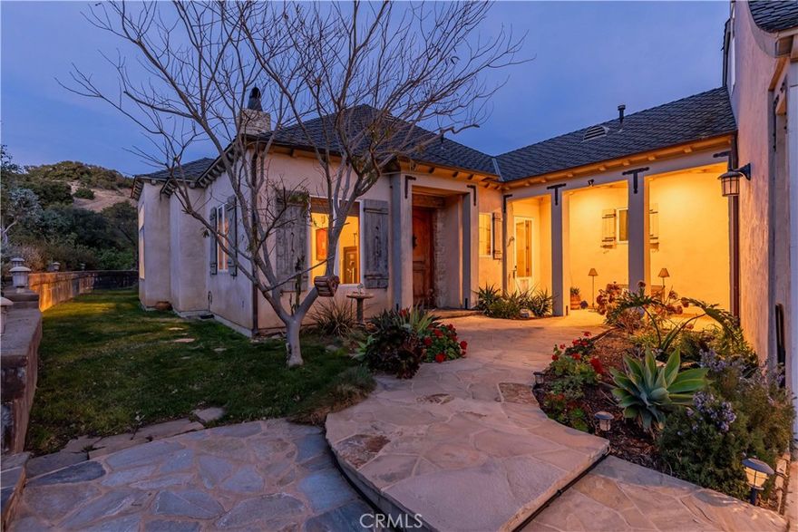 Discover unparalleled elegance in the prestigious De Luz community of Temecula, where this French Country estate offers a harmonious blend of luxury and natural beauty. Set on over five acres, this 3,024 sq. ft. custom-built home is designed for those who seek sophistication and seclusion while remaining just minutes from Old Town Temecula, world-class wineries, and convenient freeway access. The property also includes a separate, beautifully designed 665 sq. ft. apartment above the three-car garage. With its own private entrance, full kitchen, bathroom, and a patio offering breathtaking views, it is perfect for guests, extended family, or as a potential rental. Every detail of this three-bedroom, five-bathroom home exudes quality and craftsmanship. The open floor plan features radiant heated hardwood floors with four customizable zones, soaring 12-foot ceilings, alder wood doors, handcrafted wood, and stone accents. A stunning stone fireplace anchors the living space, while oversized wood-framed windows flood the home with natural light. The chef’s kitchen is a culinary dream, boasting a Jenn-Air six-burner range with a grill and double ovens, stainless steel appliances, green granite countertops, custom cabinetry, a walk-in pantry, and a spacious center island with a vegetable sink. The sunny breakfast nook offers stunning views of the De Luz countryside, creating the perfect backdrop for morning coffee. The expansive primary suite is a serene retreat, complemented by a spa-like bathroom. A generously sized office and an enormous laundry room with abundant storage add to the functionality of this home. The grounds feature approximately 400 professionally managed avocado trees, producing over 31,000 pounds annually, alongside a variety of fruit trees. A handcrafted stone walkway leads through lush landscapes reminiscent of a private winery, while night lighting transforms the property into a magical retreat after sunset. The gated entry, complete with an ornate stone and wrought iron, sets the stage for this one-of-a-kind estate. The long, scenic driveway, surrounded by cypress and pine trees, welcomes you home to a place where craftsmanship and nature unite. Experience the essence of Temecula living with breathtaking views, timeless design, and unmatched tranquility.