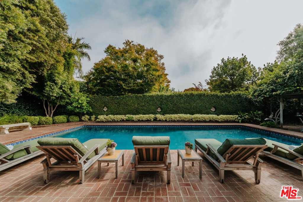 Situated in the prestigious Huntington neighborhood of the Pacific Palisades, this exquisite family home effortlessly blends historic charm with contemporary elegance. Once owned by famed author Henry Miller, this glamorous Monterey Colonial estate boasts an unparalleled pedigree, while being moments away from the renowned Palisades Village. Upon entry, reflect upon the beauty of the gorgeous hydrangeas and mature trees gracefully leading to the entrance of the home. Step into a timeless formal living room bathed in natural light that exudes the lavish aura of Hollywood glamour. This exquisite space features floor-to-ceiling windows, a striking wood-burning/gas fireplace, and a grand piano. Continue to the formal dining room and gourmet chef's kitchen, showcasing top-of-the-line appliances including a premium Viking stove, dual Miele ovens, a Sub-Zero refrigerator, Miele dishwasher, and refrigerated wine storage. The custom cabinetry, adorned with original brass handles, provides a touch of vintage allure, offering a perfect balance between modern convenience and enduring style. The open-concept floor plan seamlessly connects the kitchen, family room, and additional dining area, centered around a cozy wood-burning/gas fireplace, while the oversized bay windows and French doors frame and open to a serene, vast, south-facing private backyard. The main level is completed by a stately home office, a secluded en-suite guest bedroom with a private entrance, and a dedicated laundry room. Upstairs, discover the expansive primary suite, highlighting two walk-in closets, and a lavish spa-inspired bath. Two private balconies extend from the suite, inviting you to step outside and enjoy fresh air and stunning views, while enjoying your morning coffee or an evening sunset. Three additional guest bedrooms and two full bathrooms round out the top floor. Outside, discover your own private paradise with a sprawling pool, rich in Hollywood history, once a favorite retreat for stars like Jack Nicholson and Warren Beatty. The lush garden is complemented by a grand covered pergola, providing the perfect backdrop for both lively gatherings and quiet moments of relaxation. An outdoor barbeque and dedicated pool bath ensure utmost convenience tailored to discerning tastes. Exclusive to Huntington residents, enjoy a private key-accessed park that offers stunning ocean views, a designated dog run, and a serene garden setting. Don't miss this rare opportunity to own a meticulously maintained, very special home in one of Pacific Palisades' most coveted locations.