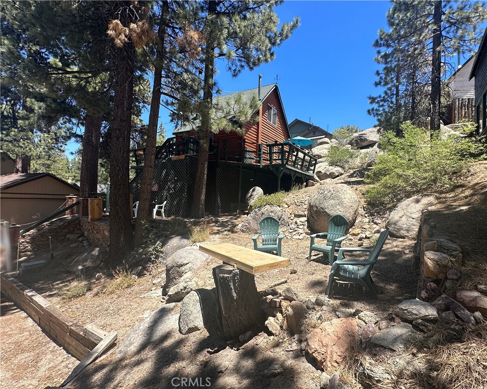 Charming Boulder Bay log cabin nestled beneath shady pines and tucked against a bed of grey boulders! Fully furnished and also includes a 16' 1962 Classic Sea King BOAT with TRAILER! Enter from the wrap around deck through the glass French door into a spacious living room featuring a cast-iron wood-burning stove and serene views of the lake and surrounding trees! The adjoining kitchen boasts an antique Wedgewood stove and comes fully equipped with a refrigerator, dishes and cooking supplies. The separate cozy dining area offers a ceiling fan and views of pine trees and large boulders on the adjoining slope. Interior laundry with included washer and dryer are next to the full bathroom with tub and shower. Upstairs, you’ll find a large bright and airy bedroom with wood accented walls, tall ceiling with a lighted fan, and several closets! Enjoy the outdoors from the wrap-around deck with BBQ, a bar top, and multiple seating areas-- perfect for grilling and relaxing in nature! Additional features include forced air heating with a Nest thermostat, dual-pane windows, and a surveillance camera. A workshop and closet are conveniently located beneath the deck, and there's a parking pad right at street level. With hiking trails, the lake, and Big Bear Lake Village just minutes away, adventure and amenities are close at hand! Best of all, this cabin is sold fully furnished with a boat! Just bring your suitcase and settle in!