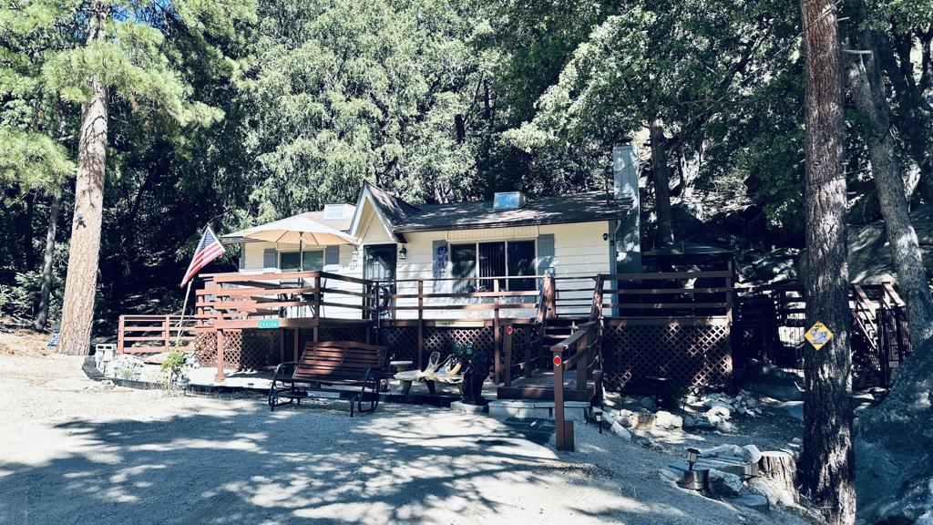 Tucked away at the end of a quiet cul-de-sac on a desirable corner lot, this inviting single-level Idyllwild home offers the perfect blend of mountain charm and modern convenience-all with easy access. Boasting 2 bedrooms and 1.5 baths across 952 square feet, the open-concept living and kitchen area is anchored by a classic brick fireplace with a wood stove insert, creating a warm and welcoming atmosphere. Dual pane windows fill the space with natural light, and the convenient laundry area adds everyday ease. Step outside to a wraparound deck overlooking a fully fenced yard that spans two lots-totaling 0.51 acres-where you'll find dramatic boulders, stone pathways, and a seasonal creek meandering through the property. Whether you're relaxing on the deck, exploring the scenic grounds, or enjoying the peaceful privacy, this home is a rare single-level retreat, ready for it's new owners to make it theirs.