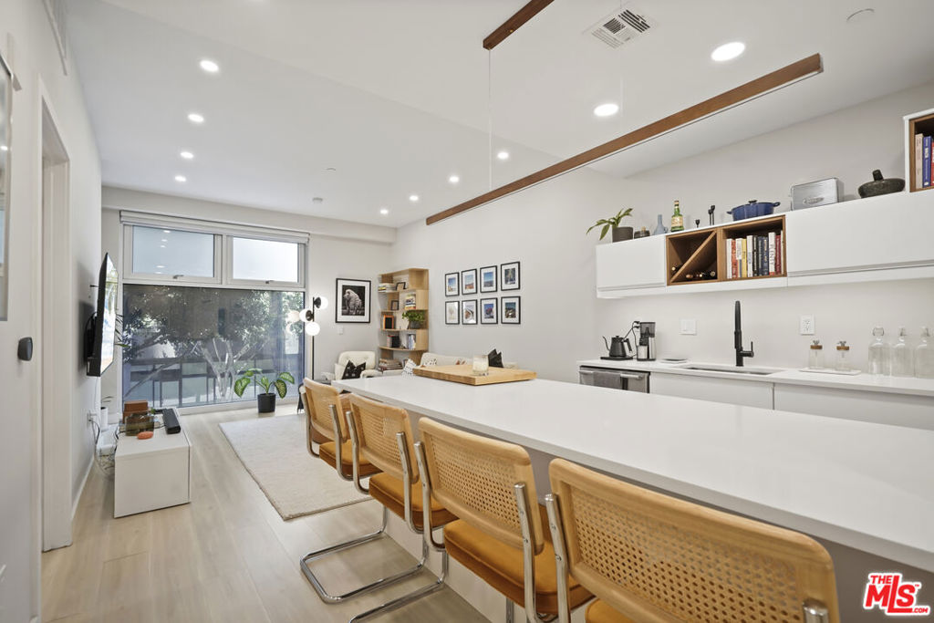 Furnished retreat at Library Court with direct access to a tranquil open courtyard. This thoughtfully furnished 1-bedroom, 1-bath condo offers a modern, turnkey living experience in the heart of Downtown LA. The spacious, open-concept design blends sleek lines with warm, organic touches highlighted by light wood flooring, recessed lighting, minimalist furnishings, and curated details throughout. The streamlined kitchen features white cabinetry, a wine nook, and an oversized island with bar seating for four. The bedroom area enjoys privacy and style, complete with a plush bed, accent wall, and designer lighting. Floor-to-ceiling windows and frosted glass panels filter in natural light while maintaining privacy. Additional features include in-unit laundry, a stylish black-tiled walk-in shower, central air and 1 assigned parking space. Offered fully furnished and move-in ready, this home is ideal for anyone seeking comfort, convenience, and downtown sophistication in one smart package.