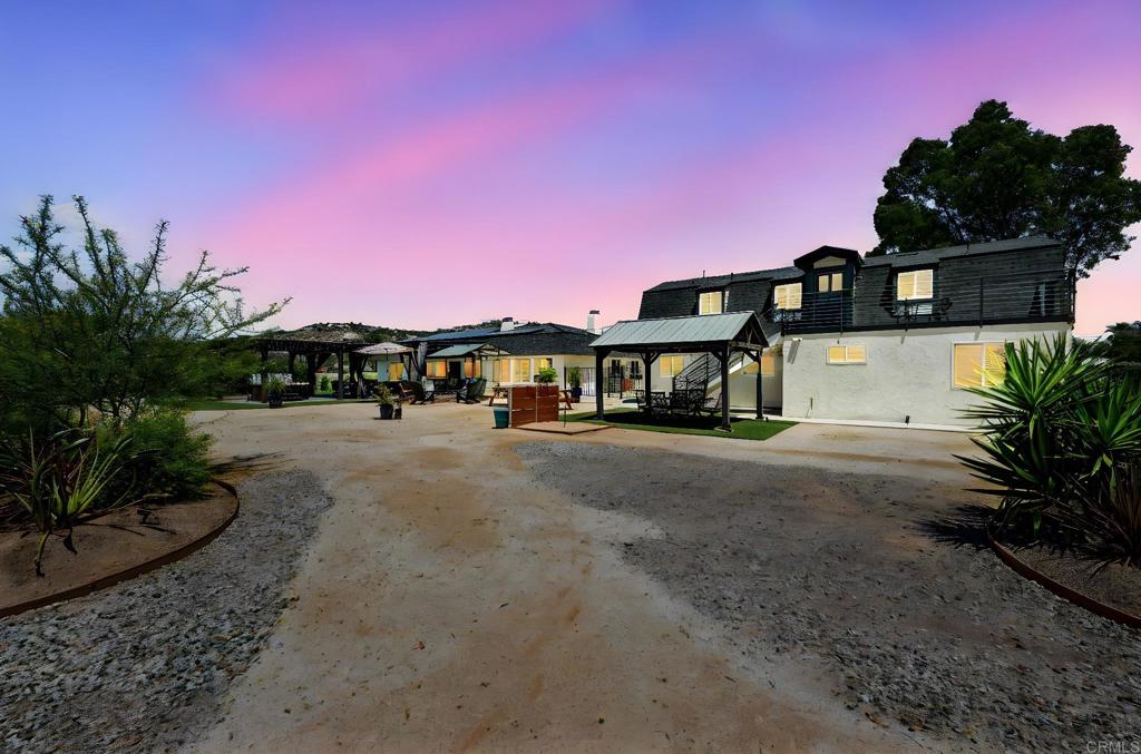 Welcome to your own private compound—nearly 3 fully usable acres of opportunity, privacy, and potential! Tucked behind secure gates with four 30-foot entrances allowing seamless pull-through access for large vehicles, this one-of-a-kind property is ideal for multi-generational living, income production, or future development. The main residence offers 3 spacious bedrooms and 2 beautifully renovated bathrooms, featuring updated plumbing, electrical, new windows, roof, fresh paint, and flooring throughout. Just steps away, the detached garage boasts a fully remodeled 1 bed, 1 bath loft apartment complete with its own laundry—perfect for guests, tenants, or extended family. But that’s just the beginning—this versatile garage also includes its own full bathroom and laundry area and can easily be converted into an additional living space or ADU. And if you're looking to expand, the property includes approved plans and permits for an impressive 80'x40' metal building structure with three 18’ roll-up doors—ideal for a workshop, warehouse, or collector’s garage. Enjoy outdoor living under a stylish covered patio with built-in seating and an above-ground spa—your private retreat to unwind or entertain. This property has also proven itself as a successful Airbnb, offering strong income potential. With room to grow, space to build, and upgrades throughout, this turnkey estate is a rare opportunity for homeowners, investors, and visionaries alike.