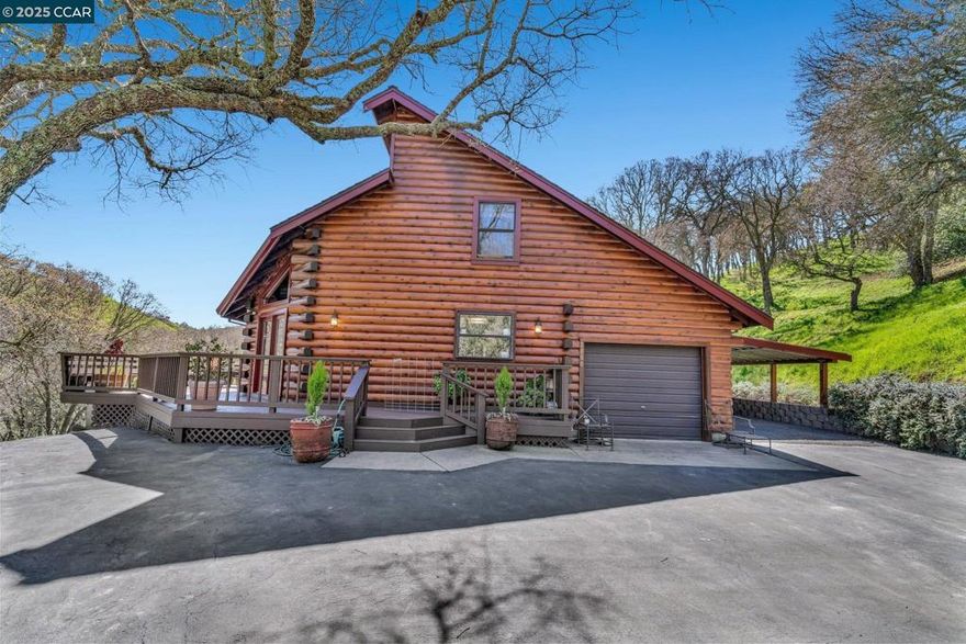 Craftsman-inspired log home with scenic views from every window. This 1,654 sq. ft. residence features 3 bedrooms (including one conveniently located on the main floor), 2 bathrooms. Large kitchen features tile counters & island with breakfast bar seating, natural wood cabinetry, all black appliances & opens to casual dining area.  The cozy mountain-inspired living room exudes rustic charm with its rich wood-paneled walls, vaulted tongue-and-groove ceiling, and exposed wooden beams. A stunning stone & brick fireplace serves as the heart of the room, featuring an arched hearth & freestanding wood-burning stove. The property includes a one-car garage and an additional carport. Enjoy the privacy of a fenced garden and play area, and relax on the expansive wraparound deck featuring spa, perfect for taking in the natural beauty that surrounds you. This property is on approx 6.11 acres and offers a 125' x 60' covered arena which accommodates a wide range of riding styles, making this home a unique blend of comfort and functionality.