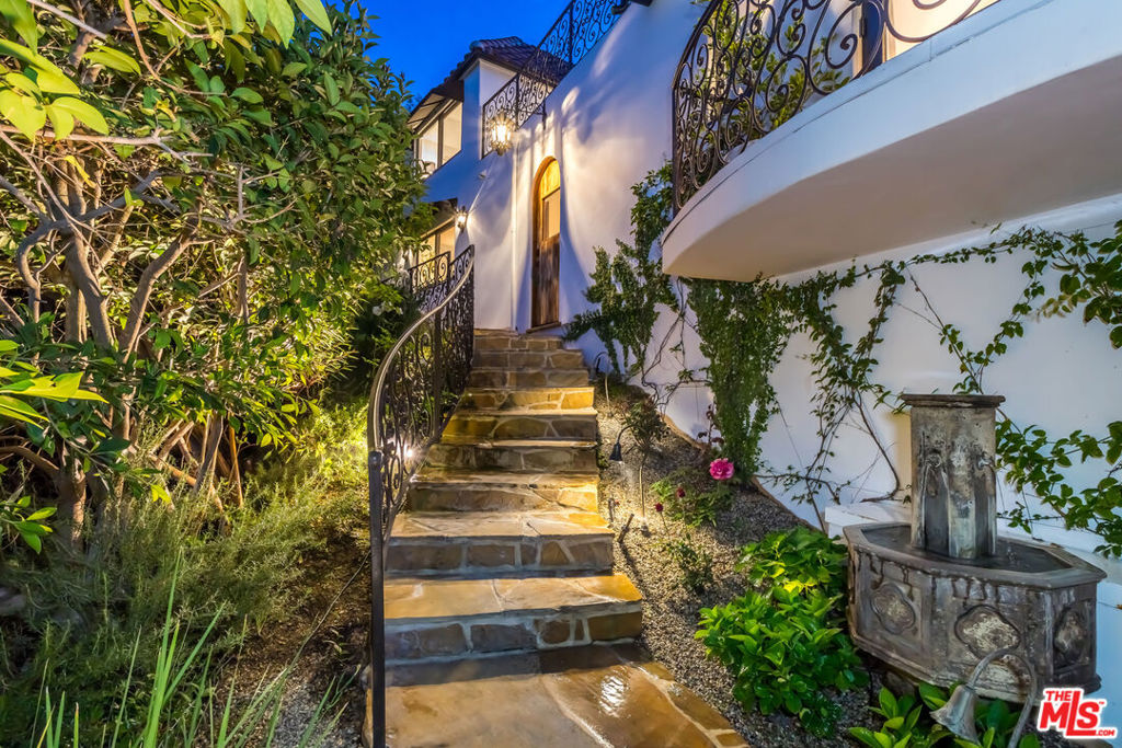 A must-see Hollywood Hills Hideaway | Unmatched Privacy + Explosive Views. At the very end of a private promontory sits this romantic Mediterranean estate, a rare jewel where timeless elegance meets modern luxury. No expense was spared in creating this fully custom home, with Waterworks fixtures, hand selected walnut hardwood floors, artisan tilework, and bespoke cabinetry throughout.The chef's kitchen features Viking appliances and a Liebherr refrigerator, opening to dramatic indoor-outdoor living spaces perfect for entertaining. Celebrity owned, with a state-of-the-art security system and rolling tamper-proof, bullet-resistant shutters, this property offers true peace of mind. The open layout flows to multiple expansive terraces, a sparkling pool, bubbling fountains, fire pit, cabana, and two additional outdoor fireplaces, all framed by sweeping, romantic views of the city. Direct three-car garage access, surround sound powered by Sonos, plus an additional covered two-car carport make for easy, secure living. Set on a large private lot with endless possibilities, this home isn't just a place to live, it's a lifestyle.