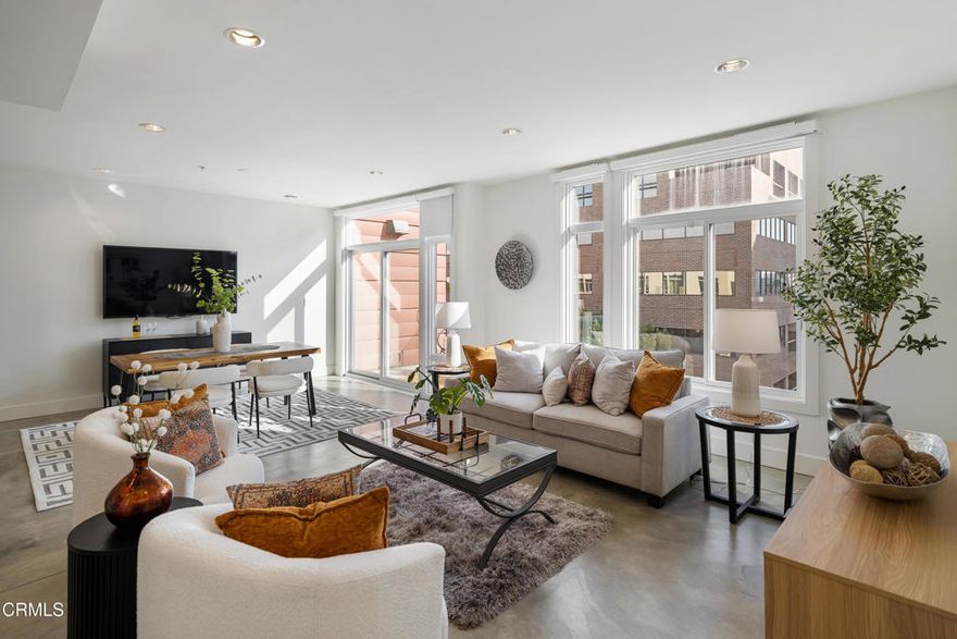 Experience sophisticated urban living in this stunning top-floor luxury condo at The Burton, one of Pasadena's most sought-after contemporary communities. As the largest floor plan in the building with only one shared wall, this residence offers an added sense of privacy and exclusivity rarely found in condo living. Designed for modern comfort and style, the open-concept layout allows the living, dining, and kitchen spaces to flow seamlessly together -- ideal for entertaining or relaxed everyday living. Polished concrete floors, recessed lighting, and floor-to-ceiling windows infuse the home with a bright, airy ambiance. The sleek kitchen features granite countertops, stainless steel Frigidaire Gallery appliances -- including a gas range, microwave, side-by-side refrigerator, and dishwasher -- along with a discreetly hidden laundry area tucked behind cabinetry for a clean, streamlined look. The living room opens to a private balcony with expansive eastern views that stretch across the city and out to the mountains -- a perfect spot for morning coffee or unwinding at the end of the day. Smart home upgrades, such as Philips Hue lighting and remote-controlled window blinds, add thoughtful convenience to the everyday experience. Down the hallway, two spacious bedrooms offer oversized windows, ceiling fans, and walk-in closets. The guest bedroom is located near a stylish full bathroom with a tub and shower combination and a sleek single-sink vanity. The primary suite is its own peaceful retreat, featuring a deep walk-in closet and a spa-inspired bathroom with stone countertops, a soaking tub, and a glass-enclosed shower. Residents enjoy oversized parking spaces located conveniently near the elevator, creating a smooth day-to-day arrival experience. Located in the heart of Pasadena, this exceptional home places destinations such as Lake Avenue shopping and dining, Old Town Pasadena, The Paseo, and the Pasadena Civic Auditorium close at hand. Easy access to the Metro Gold Line provides direct connectivity to downtown Los Angeles, and the renowned Rose Parade route is approximately one and a half blocks away -- placing local tradition and entertainment within effortless reach. With its sophisticated finishes, smart technology, sweeping views, and prized location, this top-floor residence offers elevated comfort and elegant city living at its finest.