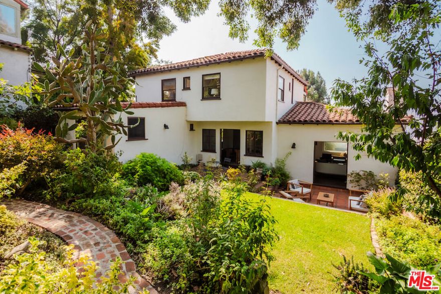 At the top of the Franklin Hills in Los Feliz, this character-filled 1932 Spanish radiates warmth, romance, and classic Los Angeles charm. A stained-glass entry sets the tone, opening to a gracious step-down living room with coved ceilings, a classic arched fireplace, and French doors that invite the outdoors in. Original details blend seamlessly with thoughtful modern updates, creating a home that feels both authentic and refreshed. The remodeled kitchen is a showpiece - bright and airy with honed marble countertops, soft green cabinetry, brass fixtures, and a custom range that anchors the space in style. A formal dining room flows effortlessly to the garden, making this level ideal for entertaining. A flexible fourth bedroom completes the main floor. Upstairs, a grand curved staircase with artisan tile risers leads to three serene bedrooms and two beautifully updated baths. The front bedroom opens to a romantic balcony framing postcard views of the Griffith Observatory, city lights, and surrounding hills - scenes that remind you you're in one of L.A.'s most storied neighborhoods. Outside, terraced gardens and multiple patios offer a private, sun-soaked escape for al fresco dining, morning coffee, or gatherings under the stars. A flat grassy area, fruit trees, and mature landscaping surround the home in natural beauty. Additional highlights include an attached garage with direct access and a basement storage room. Located moments from both Los Feliz & Silver Lake with favorites like All Time, Maru Coffee, and Mirate, this soulful Spanish captures the essence of classic Los Angeles living where historic character meets effortless everyday comfort. Located in the Franklin Avenue Elementary School district.