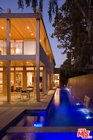 A modernist masterpiece by Master builders, Sarlan Builders, this Six bedroom residence located in Santa Monica is a feat in 21st century architecture. Stacked flagstone and smooth concrete dominate the exterior facade for a statement that is sleek and fortified while towering double entrance doors open to offer a clear line of sight all the way to the home's lush backyard landscape. By merging contemporary design principles with inviting alfresco spaces, like the extended 65 foot lap pool/spa and covered patio, this residence provides year-round enjoyment as well as a 2-story guest house. Sunlight cascades through thoughtfully placed windows and a walkable 30 foot-long skylight illuminating the lower level. Distinct flooring, wood overhangs, and exposed wooden beams add warmth to the interiors, which include a glass-lined staircase leading to a game-room converted basement where natural concrete flooring and walls enhance its industrial appeal.