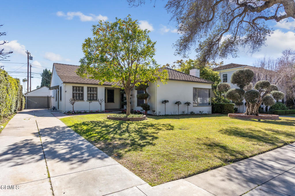 This charming single-story home is located in the award-winning San Marino School District and offers expansive grounds and well-maintained interiors. A brick-accented fireplace anchors the bright living room, featuring large windows with a picturesque view of the front yard and neighborhood. The formal dining room is enhanced by wainscoting and chair rail molding- ideal for both everyday meals and entertaining. The updated kitchen includes granite countertops, tile flooring, and double sinks. It adjoins a cozy breakfast room with built-in buffet cabinetry. Connected to the breakfast room is a versatile home office with its own private entrance from the driveway is perfect for remote work. A spacious laundry room with utility sink and built-in storage offers access to the backyard. The west wing features a hallway lined with linen closets, a full bath with separate tub and stall shower, and a bright front bedroom with ample closet space. The central bedroom has a walk-in closet, en-suite 3/4 bath, and views of the backyard. A den/sitting room with built-in bookshelves, 3/4 bath, and wall A/C connects to the rear bedroom, which opens to a spacious patio via sliding doors. The backyard is perfect for SoCal outdoor living, complete with a sparkling pool, multiple patio areas, and refreshed landscaping. A long gated driveway leads to a detached 2-car garage. Additional highlights include newer interior and exterior touch-up paint, custom window coverings, and hardwood floors throughout. This well-cared-for home is move-in ready and offers comfort, functionality, and charm in a highly sought-after neighborhood.