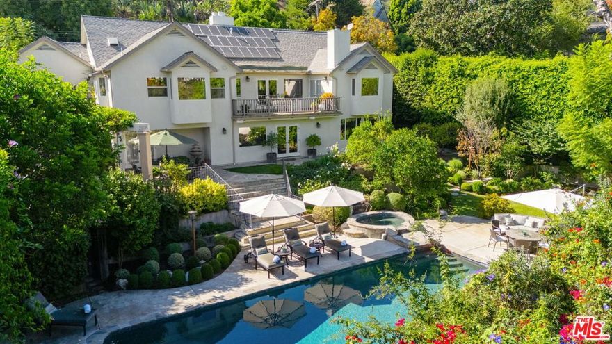 Behind discreet walls and gates, what appears to be a small hillside home, reveals a hidden estate that once served as a rock star's retreat. Step through the front door and into the formal entry to find that you are on the 2nd floor of a large 2-story home. On this level, the expansive living room features a fireplace and French doors leading to a breathtaking balcony/patio with views overlooking the serene backyard. There is a sophisticated dining room and a generously sized, eat-in, cook's kitchen. The primary suite offers ample, spa-like space, while an additional bedroom and a third bedroom, situated in its own private wing, ensure privacy. Each bedroom is complemented by its own en-suite bathroom. The lower level is designed for entertainment and self-care, boasting a spacious family room, exercise room, separate sauna, and a fourth bedroom with en-suite bath. An office, overlooking the garden, offers versatility as a potential fifth bedroom. Additional features include a dedicated 800 bottle wine cellar, 6th bathroom, a convenient laundry room, and owned solar panels and back-up battery. Outside, enjoy an idyllic sanctuary with lush greenery creating a natural privacy barrier around the pool and spa, grassy play area, fire pit, and gourmet outdoor kitchen and bar complete with a wood-burning pizza oven. This secluded oasis provides easy access to both the valley and city, offering proximity to dining, shopping, renowned entertainment, and scenic hiking trails.