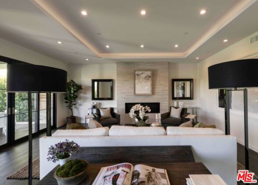 Discover modern California luxury in this sophisticated Mar Vista Hills residence, located within the highly sought-after Mar Vista Elementary School District. Thoughtful landscaping and clean architectural lines create a warm welcome, leading into a sunlit foyer with dramatic volume and seamless flow. An open-concept layout connects the spacious living room to a chef's kitchen featuring a generous island and professional-grade Viking appliances. Sliding glass doors blur the line between indoor and outdoor living, opening to a covered, heated patio and a tranquil backyard oasis complete with a heated pool (not shown in photos), perfect for entertaining or quiet relaxation. Designed for today's lifestyle, this smart home features a 125-inch 4K projector with retractable screen, a Tonal gym (one of the five en-suite bedrooms), Tesla solar panels, and a Tesla EV charging station, a perfect blend of comfort, technology, and sustainability. The home offers five bedrooms and five and a half baths, including a first-floor en-suite bedroom ideal as an office or guest suite. Upstairs, the primary suite provides a serene retreat with a spacious private patio, while the additional bedrooms each feature en-suite bathrooms for privacy and convenience. Ascend to the rooftop deck and take in breathtaking 360-degree views spanning the Hollywood Hills, Downtown LA, and the Pacific Ocean. With a gas fire pit and wet bar, it's the ultimate space for relaxation or entertaining beneath the stars. Note: Current photos are from the home's 2018 sale. Since then, the property has been enhanced with new smart-home features, updated furnishings, and different artwork.