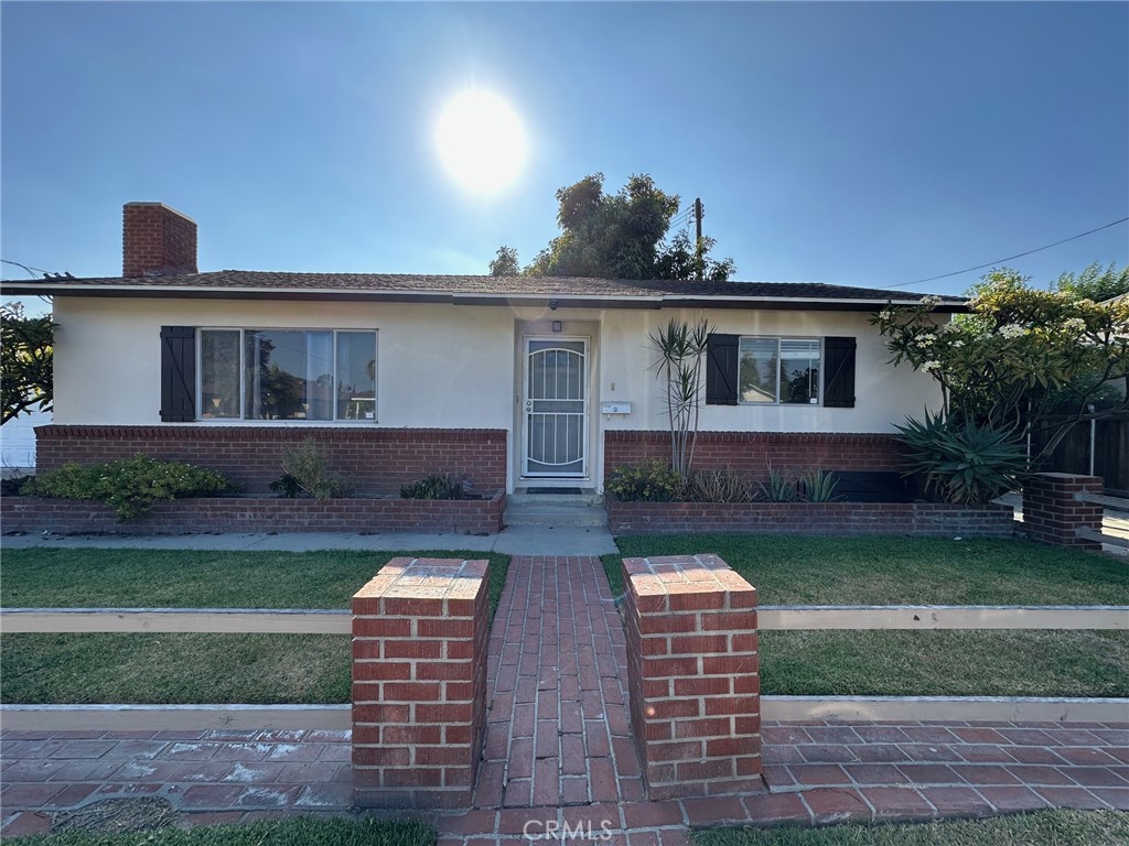 This this charming 2 bedroom and 1 bathroom home—perfect for a small family or a starter family. The property boasts excellent curb appeal with classic brick pillars. A brick walkway leads to the front entrance, which features a four-panel door with an upper glass insert and a secure metal screen door. Inside, the cozy living room showcases a brick-faced fireplace, limonite flooring, and plenty of natural light. Comfort is ensured with wall/window air conditioning, ceiling fans, and a floor heating system. All windows include screens and coverings for privacy and climate control. The kitchen offers tiled countertops, painted cabinetry, and a gas hookup for a stove/range. It connects directly to the laundry area, which also includes a gas hookup. An attached two-car garage with a metal door provides rear yard access. The backyard is low-maintenance and includes a small grassy area, fruit and citrus trees.