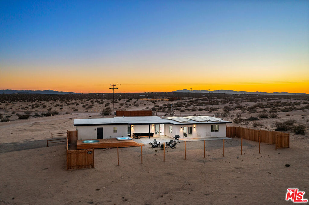 A midcentury spirit meets modern desert magic in this fully reimagined home, set on five expansive acres beneath the boundless skies of the high desert. Every detail has been thoughtfully considered: sleek quartz countertops gleam in the kitchen, dramatic statement beams anchor the sunlit great room, and clean modern finishes offer effortless style. Outdoors, the desert becomes your playground. A newly built wood deck cradles the hot tub and cowboy tub - perfect for sunrise dips or starlit soaks - while framing breathtaking mountain views that shift and glow with the desert light. The acreage invites possibility: add an ADU, build a pickleball court, subdivide the lot, or simply savor the wide-open space. Investors will appreciate the property's proven appeal to desert travelers seeking unique, design-forward stays, as well as the expansive acreage that offers room to scale with future additions. Practical upgrades abound, including newer windows, doors, roof, septic, insulation, electrical, mini-splits for year-round comfort, and leased solar for sustainable living. This home is as functional as it is enchanting. When wanderlust calls, Joshua Tree National Park and the vibrant heart of 29 Palms - farmers market, eclectic dining, and desert nightlife - are just minutes away. Equal parts chic retreat and desert reverie, this is a home designed for style, serenity, and star-studded skies.
