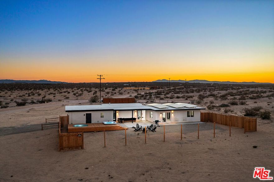 A midcentury spirit meets modern desert magic in this fully reimagined home, set on five expansive acres beneath the boundless skies of the high desert. Every detail has been thoughtfully considered: sleek quartz countertops gleam in the kitchen, dramatic statement beams anchor the sunlit great room, and clean modern finishes offer effortless style. Outdoors, the desert becomes your playground. A newly built wood deck cradles the hot tub and cowboy tub - perfect for sunrise dips or starlit soaks - while framing breathtaking mountain views that shift and glow with the desert light. The acreage invites possibility: add an ADU, build a pickleball court, subdivide the lot, or simply savor the wide-open space. Investors will appreciate the property's proven appeal to desert travelers seeking unique, design-forward stays, as well as the expansive acreage that offers room to scale with future additions. Practical upgrades abound, including newer windows, doors, roof, septic, insulation, electrical, mini-splits for year-round comfort, and leased solar for sustainable living. This home is as functional as it is enchanting. When wanderlust calls, Joshua Tree National Park and the vibrant heart of 29 Palms - farmers market, eclectic dining, and desert nightlife - are just minutes away. Equal parts chic retreat and desert reverie, this is a home designed for style, serenity, and star-studded skies.