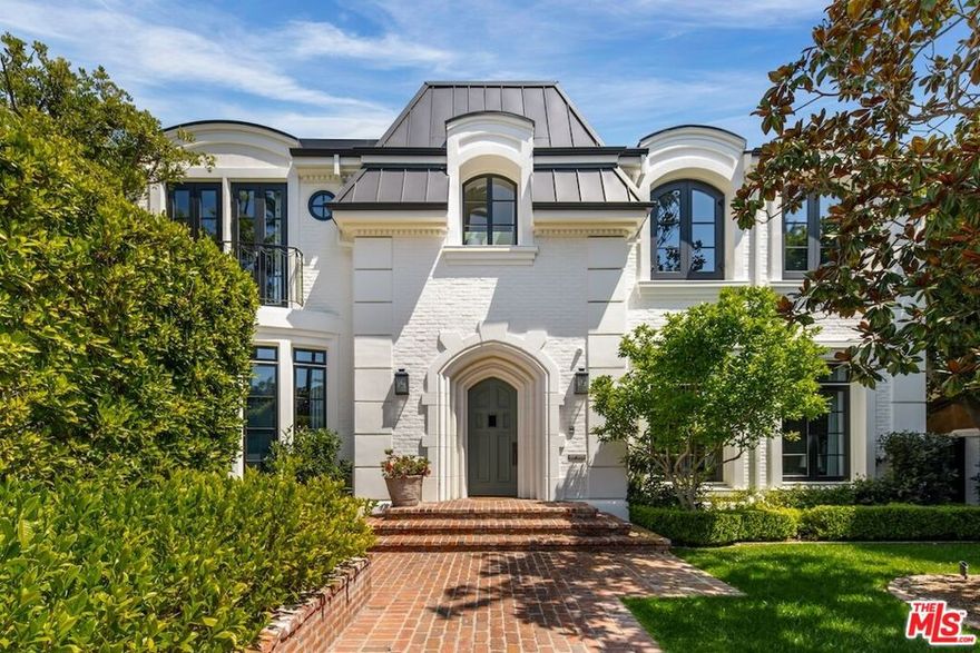 This paragon of traditional architecture is nestled privately behind mature hedges and a gate on a flat, half-acre in the heart of the prestigious flats of Beverly Hills. The estate has been newly curated and furnished under the masterful guidance of designer Michael S. Smith, following his transformation of the White House's private residence. The entry makes an unforgettable statement with hand-painted chalky-stri walls by Maria Trimbell, custom bronze sconces by French sculptor Patrice Dangel, and a sweeping iron staircase adorned with a silk-and-wool runner by Patterson Flynn. In the formal living room, Venetian plaster walls and a Calacatta Viola marble fireplace by Jamb London create an atmosphere of quiet opulence. The dining room stuns with hand-painted Gracie wallpaper and a 19th-century Spanish crystal chandelier. The gourmet chef's kitchen is a study in refined craftsmanship, decorated by Calacatta marble countertops, and state-of-the-art appliances, ensuring peak culinary performance. A large central island offers both ample work and gathering spaces. Thoughtfully situated adjacent to the kitchen, the den duals as a screening room, punctuated by custom walnut paneling, a hand-carved limestone fireplace, and bespoke millwork. The lushly landscaped grounds create a private oasis, featuring a resort-style pool and spa, surrounded by manicured gardens and mature hedging. A detached guest house/gym adds versatility, while multiple outdoor seating areas, a shaded loggia, and elegant hardscaping set the stage for alfresco entertaining. The primary suite is a serene retreat, highlighted by a private sitting room, dry sauna, fireplace, and a private terrace. Dual spa-inspired bathrooms are equipped with Waterworks fixtures, radiant heated floors, and expansive closets with custom dressing rooms. Designed for both relaxation and hosting, 610 North Canon represents a confluence of timeless elegance with contemporary sophistication. This  one-of-one trophy property is situated only moments from the world class dining, shopping, hotels, and attractions only downtown Beverly Hills living has to offer.