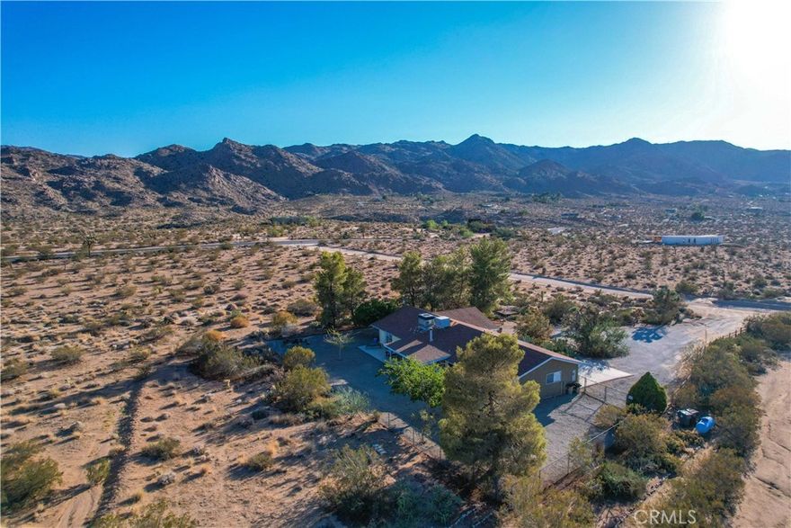 Live your best life in this spacious showplace on 2.5 acres with breathtaking 360 degree mountain views in the coveted Monument Manor neighborhood. Near the west entrance to Joshua Tree National Park, this 1,840 sq. foot 3 bedroom, 2 bathroom, pine shaded oasis offers comfortable and stylish living in a stunning natural environment. An entertainer’s delight, this home boasts a generous open floor plan. The chef’s kitchen -- featuring stainless steel appliances and a breakfast bar -- opens into a roomy dining nook and vast, inviting living area with a cozy wood burning stove and French doors that open onto the expansive covered patio. The bedrooms are sizable and the bonus room with a private entrance presents space for a yoga room, office, or studio. Among this gem’s many charms are gorgeous coated concrete floors, recessed lighting, and ample windows that bathe the space in natural light. Beyond its beauty, this home is very well-suited for practical living, with central HVAC and ducted Mastercool, dedicated laundry area, and 2 car attached garage. Wake to the sound of chattering quail as dawn pinks the horizon and enjoy coffee on the patio. Take a hike in nearby Joshua Tree National Park, and later, enjoy stargazing while listening to coyotes sing. Truly the best deal in the best area. Don’t miss this one -- come see today!