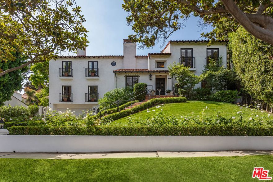 Located on prestigious Comstock Avenue in exclusive Little Holmby, this exquisite Spanish estate offers 4 bedrooms, 4 bathrooms and 2 powder rooms. Thoughtfully reimagined for modern living while preserving its architectural character, the residence celebrates timeless details with exposed wood-beamed ceilings, soft arches, wrought-iron accents and the warmth of natural materials like Saltillo tiling, wood and stone. A soaring two-story foyer with a dramatic staircase and artisan ironwork set the stage. Throughout, original elements meet elevated updates: hand-hewn beams, marble finishes and sunlit rooms. The main level features a versatile office with custom built-ins and a charming den/study with a corner fireplace. The pristine eat-in kitchen is anchored by terracotta tile floors, Calacatta marble countertops, generous storage and an adjoining breakfast room. The well-appointed, generous formal dining room, designed for entertaining, connects seamlessly to the terrace and pool through French doors, while the formal living room, framed by a grand fireplace and exposed wood beams exude sophistication. The spacious family room with soaring ceilings, Juliet balconies and dual sets of French doors creates effortless indoor-outdoor flow to expansive terraces for dining, lounging and entertaining. Upstairs, the ambient light-filled primary suite serves as a sanctuary with Juliet balconies, a fireplace, a secure custom walk-in closet with additional custom built-ins and a marble-clad bathroom featuring a soaking tub, standing shower and dual vanities. French doors open to an expansive terrace overlooking the lushly landscaped grounds. Two additional bedrooms complete the upper level, one with Juliet balconies, the other a junior suite with terrace access and bespoke storage.The lower level reveals a private guest bedroom suite with its own entrance, along with a laundry room, abundant storage, a two-car garage and a private gym with separate exterior entrance.Outdoors, towering hedges and mature trees, envelope the verdant grounds in privacy. Blooming flowers frame the sparkling swimming pool and spa, while a covered cabana with powder room, built-in barbecue and multiple alfresco dining and lounge spaces create a resort-like setting. With thoughtful modern amenities and effortless proximity to UCLA, Westwood Village, Beverly Hills, and Century City, this residence presents a rare opportunity to experience the beauty, privacy and prestige of Little Holmby living.