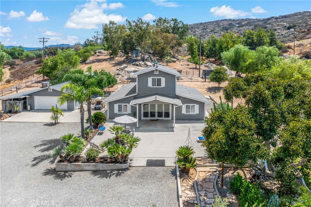 Scenic Hilltop Retreat with Expansive Views on 20 Private Acres. Welcome to your own private sanctuary—this beautifully maintained 2-bedroom, 3.5-bathroom, 2,458 sq ft two-story home sits atop 20 acres of usable land, offering both comfort and versatility in a peaceful, secluded setting. Pride of ownership is evident throughout, from the freshly painted exterior, to the well organized and maintained grounds, to the thoughtfully designed interior spaces. Energy efficiency is top of mind with paid solar and a whole-house Generac generator, providing peace of mind and lower utility costs. A detached 2-car garage and an electric gated entry enhance both functionality and security. The expansive front patio offers panoramic valley and mountain views, surrounded by inviting, mature landscaping—an ideal space for relaxing or entertaining. Step inside to discover tiled flooring throughout the main level, anchored by a stunning great room with soaring ceilings, 3" wood shutters, dual-pane windows, and stylish ceiling fan/light fixtures. The primary suite on the main floor features a spacious bedroom, dual-sink vanity, large walk-in shower, and a separate soaking tub—your own private retreat. The galley-style kitchen is equipped with a refrigerator, microwave, and electric oven/range, perfect for everyday living. An oversized laundry room offers ample storage and includes a second full bathroom with a shower. Upstairs, the home transforms into a second living space, complete with its own kitchen, generous bedroom, and cozy living room—all offering sweeping views of the surrounding landscape, including the shimmering Diamond Valley Lake and city lights of Hemet. The entire property is fully fenced, featuring a separate fenced rear area, a well-finished structure ideal as a chicken coop or dog kennel, and a large storage shed. There's plenty of space for expansion, whether you envision building additional residences, a workshop, orchards, or equestrian facilities. Tucked away at the end of a quiet cul-de-sac, this property offers true tranquility—yet it is just 15 minutes from all conveniences and only 20 minutes to Temecula’s world-renowned wine country. This is more than just a home—it's a lifestyle. Experience privacy, potential, and panoramic beauty all in one extraordinary property.