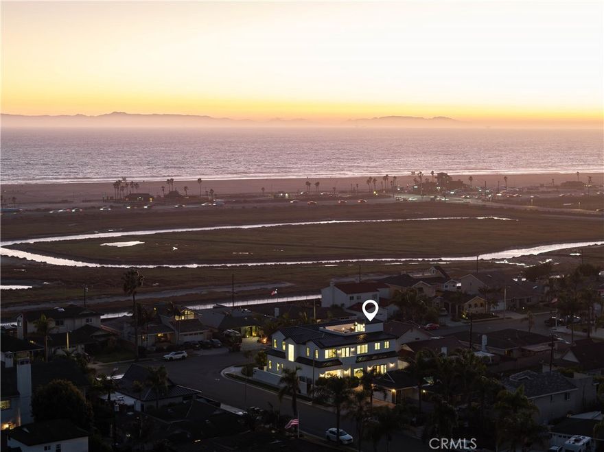 Completed in 2025, this brand-new coastal estate at 9121 Christine Drive sets a new standard for luxury in Huntington Beach. Positioned on a premier corner lot, the home offers nearly 5,000 sq. ft. of living space and a spectacular 560 sq. ft. rooftop deck with unobstructed ocean views. Designed with both form and function in mind, it combines timeless architectural detail with state-of-the-art construction and absolutely premium materials. Step inside to soaring 11-foot ceilings adorned with custom wood beams, wide-plank European white oak flooring, and natural light streaming through Milgard windows and French doors. Indoor and outdoor living flow seamlessly thanks to a dramatic La Cantina pocket door that opens to the main entertaining space, anchored by a Belvedere book-matched marble fireplace. The main kitchen showcases white oak cabinetry, Taj Mahal quartzite counters, a 72” Sub-Zero refrigerator, 48” Wolf range, and Sub-Zero wine fridge. A separate butler’s kitchen, with Thermador appliances and a walk-in pantry, ensures effortless hosting. The primary suite is a true retreat with vaulted ceilings, a stone fireplace, alabaster marble chandeliers, and a 30-foot balcony capturing ocean breezes. Its spa-inspired bath boasts full-slab marble shower walls, a custom double vanity with Brizo polished gold fixtures, and a boutique-style walk-in closet with illuminated white oak cabinetry. Additional highlights include a three-car garage with custom rift oak doors, an elevator servicing all levels, two laundry rooms, a solar system, and a durable metal roof. Designer guest baths feature Porcelanosa and Ann Sacks tile, while a Taj Mahal quartzite wet bar adds sophistication to the entertaining level. With no expense spared and every finish hand-selected, this one-of-a-kind residence blends architectural excellence with unmatched coastal living—moments from the sand and surf of Huntington Beach.