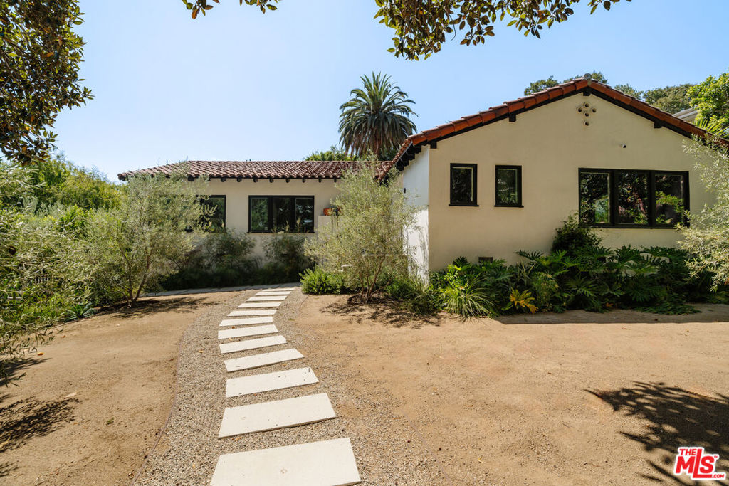 2443 N Vermont Avenue is a one-of-a-kind 4-bed, 4-bath property with guest house that was once part of the renowned Wallace Neff Los Pavoreales Estate. This Spanish style home, rebuilt in 1948 by the notable architect J. A. Murray, has been thoughtfully redesigned and seamlessly blends historic charm with modern luxury. The gated entrance leads you into a private sanctuary surrounded by mature landscaping, including bay fig trees, olive trees, and ficus hedges. Enter to the expansive living and dining rooms which feature original coved ceilings, decorative moldings, and large windows overlooking the lush surroundings. The stunning open-concept kitchen boasts custom white oak cabinetry, handcrafted Mexican Saltillo flooring and backsplash, a honed marble island and counters, and high-end appliances. The primary bedroom includes an ensuite bath with a large walk-in shower, a blue-hue Spanish tiled wall, and dual sinks. Perfect for enjoying Southern California weather, the backyard is a serene oasis with a pool/spa, built-in BBQ, and ample space for lounging and dining al fresco. The guest house, ideal for a home office or additional living space, includes a full bath and kitchenette. Situated on a large corner lot, 2443 N Vermont Avenue is conveniently located near local shops, Griffith Park, The Greek Theatre, and more.