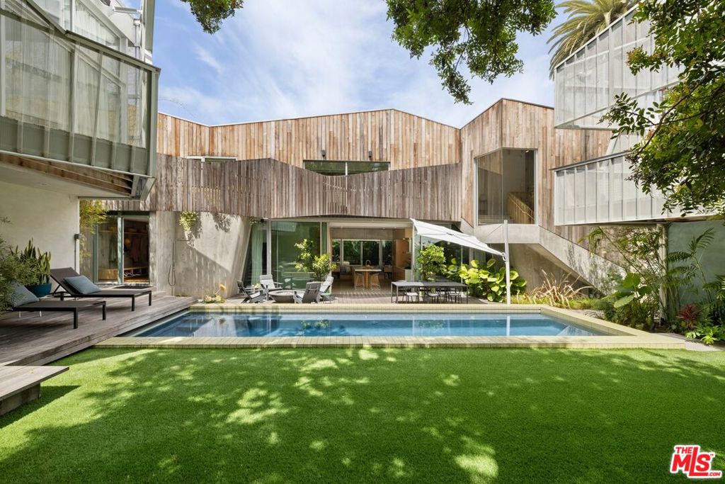 Step inside this multiple award-winning architectural compound, a dramatic conception of complimentary materials that combine to create modern serenity with multiple living structures bathed in sunlight, and a glassy pool ideally situated between. Extensively featured in the May'22 issue of Architectural Digest, no detail has been spared in this stunning showpiece. A triumph of creative design by renowned architect Kevin Daly, the property was visualized as a multi-generational estate for a contemporary lifestyle. Featuring three separate residences and offering thoughtfully conceived privacy from each one, there are endless possibilities for a seamless work/life balance amid the teeming natural surroundings and just a short walk to the famed shops and restaurants on Abbot Kinney Boulevard. The main house (Palms II, completed in 2021) spotlights warm wood and screen elements set atop a concrete podium with a a broad expanse of glass that provides open sight lines across the property. Complete with 3400 square feet of living space with 4 bedrooms and 3 1/2 baths, details include soaring ceilings, fireplace, polished concrete floors with radiant heating throughout, primary bedroom with private deck and primary bath with steam shower. The second house (Palms I, completed in 2010) places emphasis on framing discrete vistas of trees and sky with apertures arranged from folding perforated metal screens wrapped around the base structure. Complete with 2000 square feet of living space featuring 3 bedrooms and 3baths, details include soaring ceilings, open dining room, radiant floor heating throughout, kitchen with outdoor dining patio, and a living plant wall designed by Rolling Greens. The ideally positioned guesthouse finishes the third chapter of the trilogy. Artfully executed as a400 square foot studio, the space provides additional living/sleeping quarters with bath, dual sided fireplace, in-floor heating, and private deck and entrance. The outdoor courtyard is a gathering venue between the spaces, featuring 3 outdoor fireplaces, sport court with NBA regulation hoop, outdoor shower, garden and the pool with automatic retractable cover. Garage parking for six cars (3 for each home and electric chargers in both)and state-of-the-art security systems with cameras complete the practical details of this truly striking and unprecedented property.