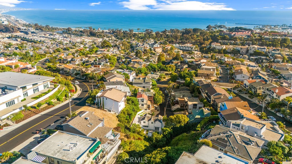 Perched at the top of a quiet cul-de-sac in the coveted Lantern District, this classic mid-century modern home blends architectural charm with modern conveniences—all just a short walk to Dana Point’s vibrant restaurants, shops, Harbor, and Doheny State Beach. Step inside to discover a thoughtfully designed layout across three levels, maximizing natural light, ocean breezes, and stunning views. The second-floor great room showcases an open dining and living area with a gas fireplace framed by an exposed concrete accent wall, leading to both a private patio and a deck with a built-in BBQ gas line for effortless entertaining. The kitchen features butcher block counters, a gas range, oven, and dishwasher. A large pantry storage, utility closet and laundry along with a convenient half-bath completes this level. Upstairs, both bedrooms connect to a spacious second living/family room. The primary suite is a true retreat, boasting dual closets, dual vanities, a skylit shower with dual showerheads, and an ocean-view sunroom perfect as a home office or reading nook. The guest suite includes its own full bath for privacy and comfort. Enjoy seamless indoor-outdoor living with a private backyard featuring mature fig trees, space for a garden, and ocean-view lounging areas. Additional highlights include: Fresh interior paint and new carpet throughout, Two-car attached garage with driveway and street parking, Ample storage including an entry-level closet, Central furnace and abundant natural ventilation from ocean breezes.