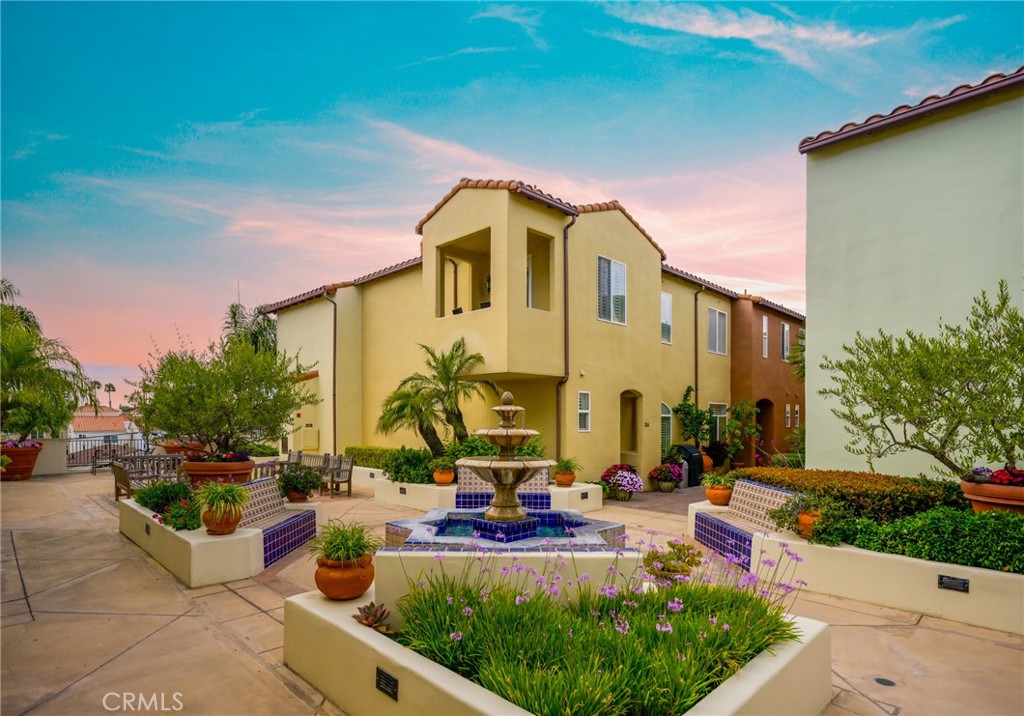 Nestled just two blocks from the sand and moments from the vibrant energy of Pacific City, this rare end-unit townhome offers a unique blend of classic style and modern coastal living. Located in the highly coveted Plaza Almeria community, this residence captures the essence of Spanish-inspired design with its crisp white stucco façade, graceful arches, serene courtyard fountain, and rich architectural detail. Positioned above charming shops and eateries along Main Street, this west-facing home enjoys peaceful views of 5th Street and golden sunsets from its private patio. Inside, an open-concept layout unfolds across two levels, featuring 2 bedrooms, 2.5 baths, and spacious living areas designed for both comfort and sophistication. Hardwood floors and a cozy fireplace welcome you into the main living room, which flows seamlessly into an expansive family area and gourmet kitchen outfitted with granite countertops and elegant tile flooring. Step outside to enjoy al fresco evenings or unwind with the ocean breeze. Upstairs, a versatile loft space is ideal for a home office or creative studio, leading to a second private patio with a view of the tranquil courtyard below. The luxurious primary suite includes dual vanities, a spa-like jetted tub, separate shower, and a generous walk-in closet. A second ensuite bedroom and convenient upstairs laundry complete the interior. Additional highlights include private storage, secure bike parking, two gated garage spaces with EV charging, and ample guest parking—offering both practicality and peace of mind. This is a standout opportunity to own a sophisticated coastal retreat in one of Huntington Beach’s most desirable locations. Schedule your tour today, this one won’t last!