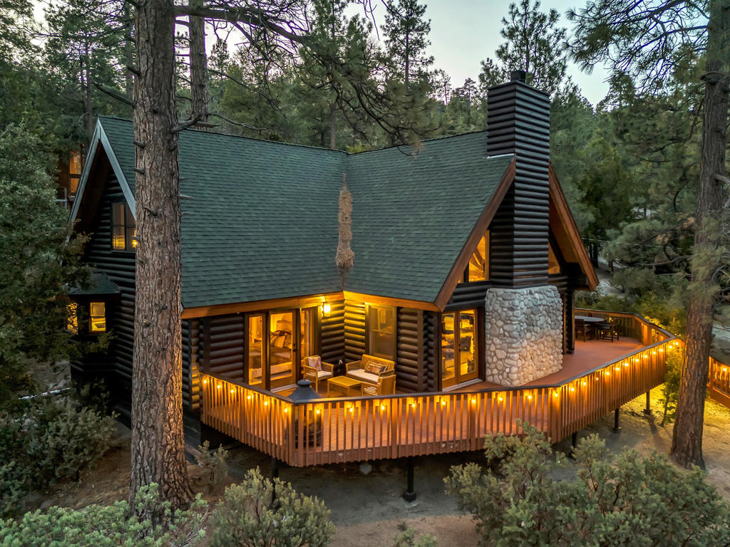 Cedar Glen Lodge is a handcrafted luxury log cabin retreat nestled in the heart of Idyllwild's serene mountain landscape. This exquisite 3-bedroom, 3-bath home blends timeless craftsmanship with refined mountain living, offering over 2,500 sq. ft. of elevated comfort and design. From the moment you arrive, you're embraced by the majestic log exterior, extensive wrap-around decks, and the tranquil ambiance of towering pines and native boulders.Inside, soaring vaulted ceilings with exposed log beams frame the dramatic great room, anchored by a floor-to-ceiling River Rock fireplace and wide-plank hardwood floors. A wall of windows fills the space with natural light and seamlessly connects you to nature's grandeur. The gourmet kitchen is a chef's dream--featuring custom cabinetry by Grand Design Kitchens, GE Cafe Matte Black and copper appliances, Neolithic quartzite island with breakfast bar seating, and an adjacent formal dining space that's perfect for entertaining.The spacious primary suite is located on the main level and feels like a private lodge within the home--complete with a spa-inspired ensuite bathroom, a large walk-in closet, and private access to the deck with treetop views. Upstairs, you'll find two additional guest rooms, a full bath, and an airy loft overlooking the living space--ideal as a reading nook, game area, or office.Outdoors, the expansive multi-level decking offers the ultimate in mountain relaxation--ideal for stargazing, al fresco dining, or enjoying your morning coffee while listening to birdsong and whispering winds. Additional features include a tankless water heater, two-car garage, HVAC, and ample storage. Comes Furnished.Located in a quiet neighborhood just minutes from town yet surrounded by nature, this home offers the rare combination of privacy, luxury, and rustic elegance. Whether you're looking for a full-time residence, mountain getaway, or investment opportunity, Cedar Glen Lodge delivers the ultimate Idyllwild lifestyle.